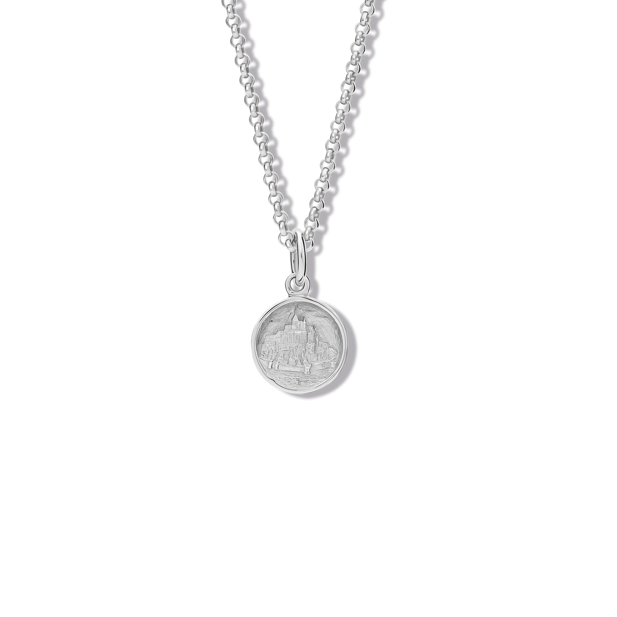 Handcrafted round sterling silver necklace pendant featuring an engraving of Mont Saint-Michel Abbey in France, hanging from a silver chain.