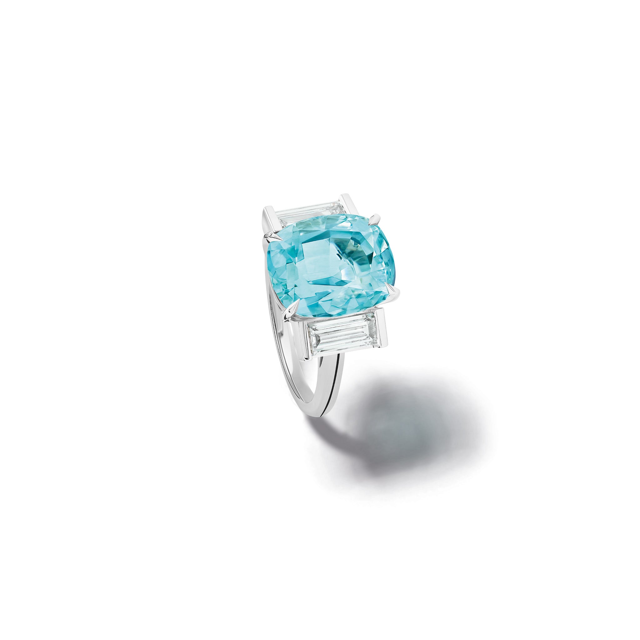 Handcrafted 18ct white gold engagement ring featuring a central oval blue aquamarine flanked by two smaller rectangular diamonds on each side, all set in a sleek band.