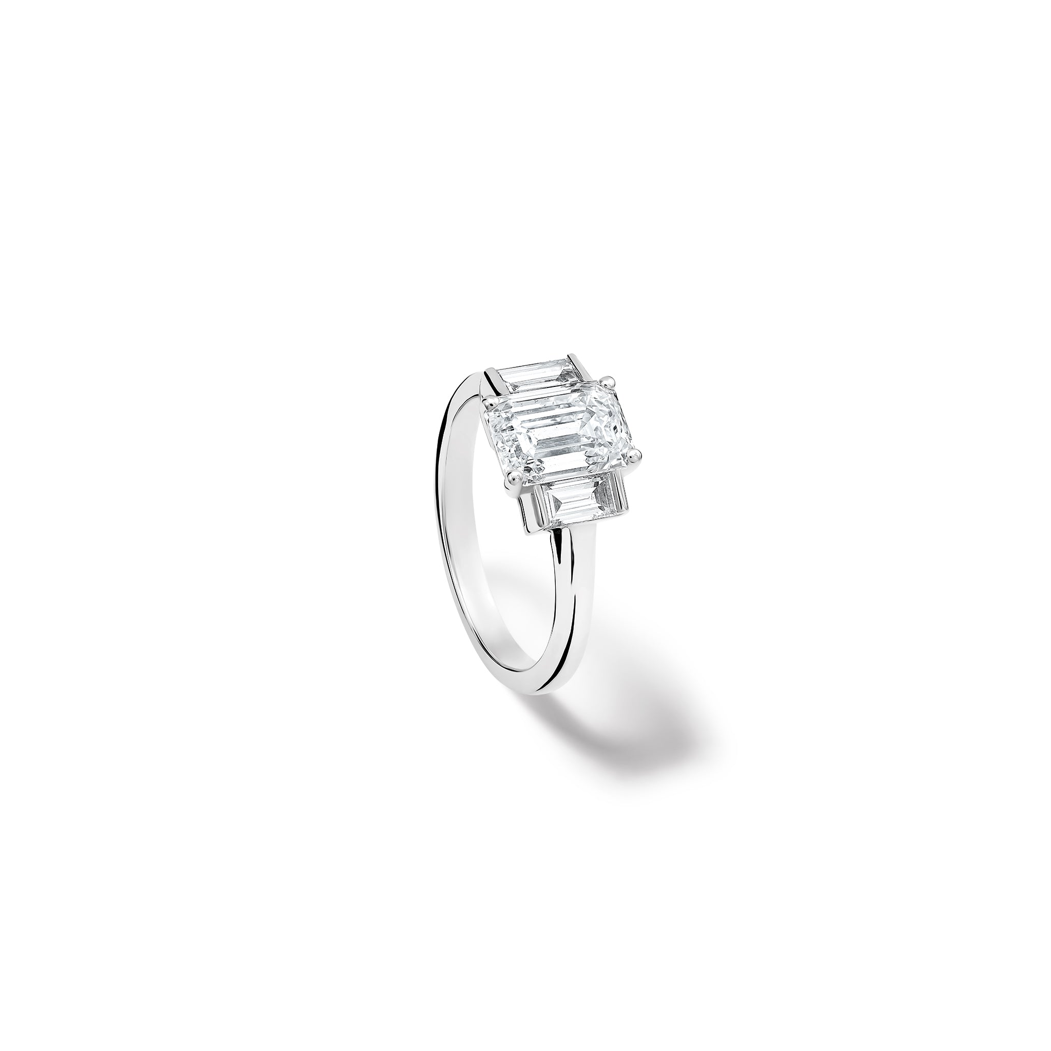 Handcrafted platinum engagement ring featuring a central rectangular diamond flanked by two smaller rectangular diamonds on each side, all set in a sleek band.