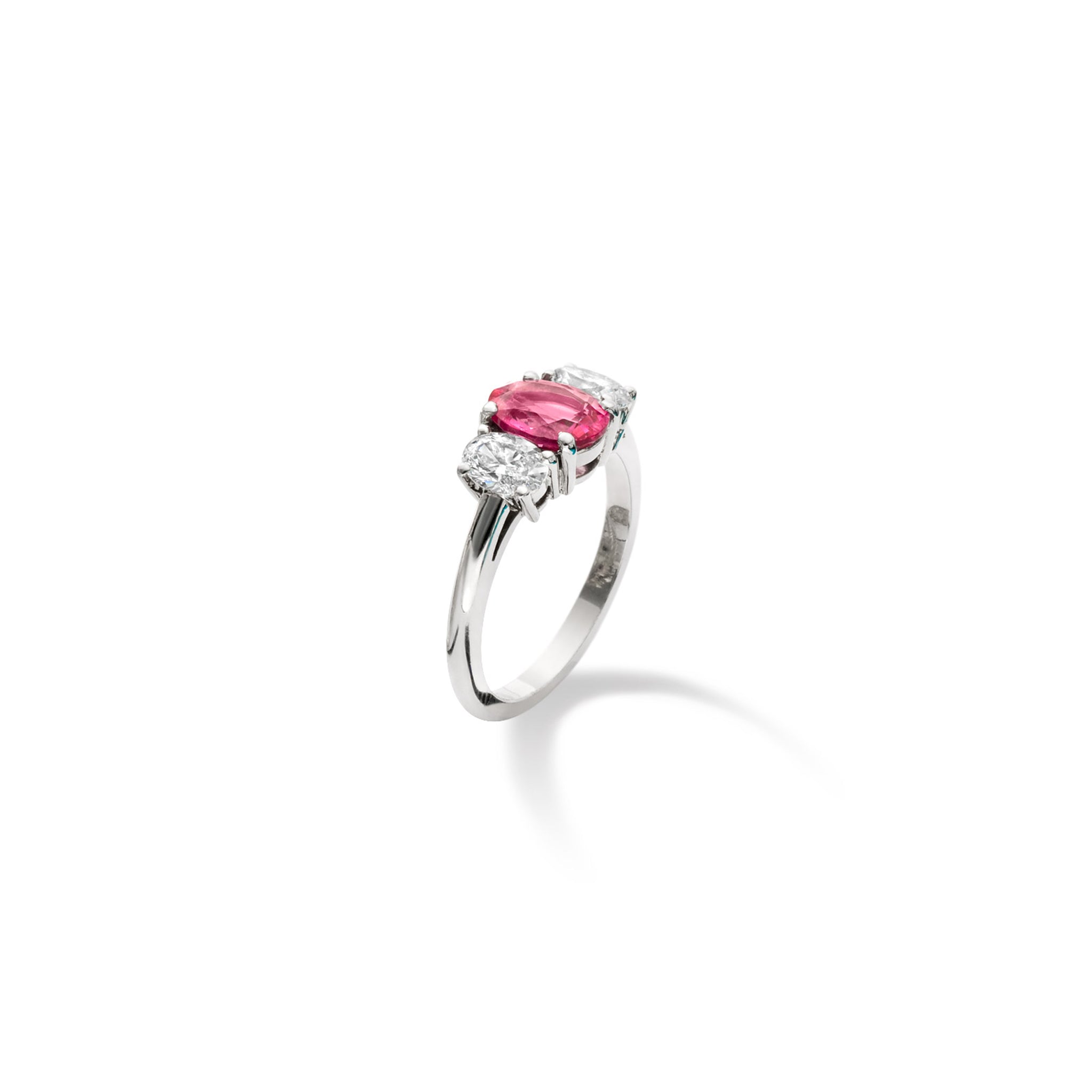 Handcrafted 18ct white gold engagement engagement ring with a large central pink sapphire flanked by two slightly smaller diamonds on each side.