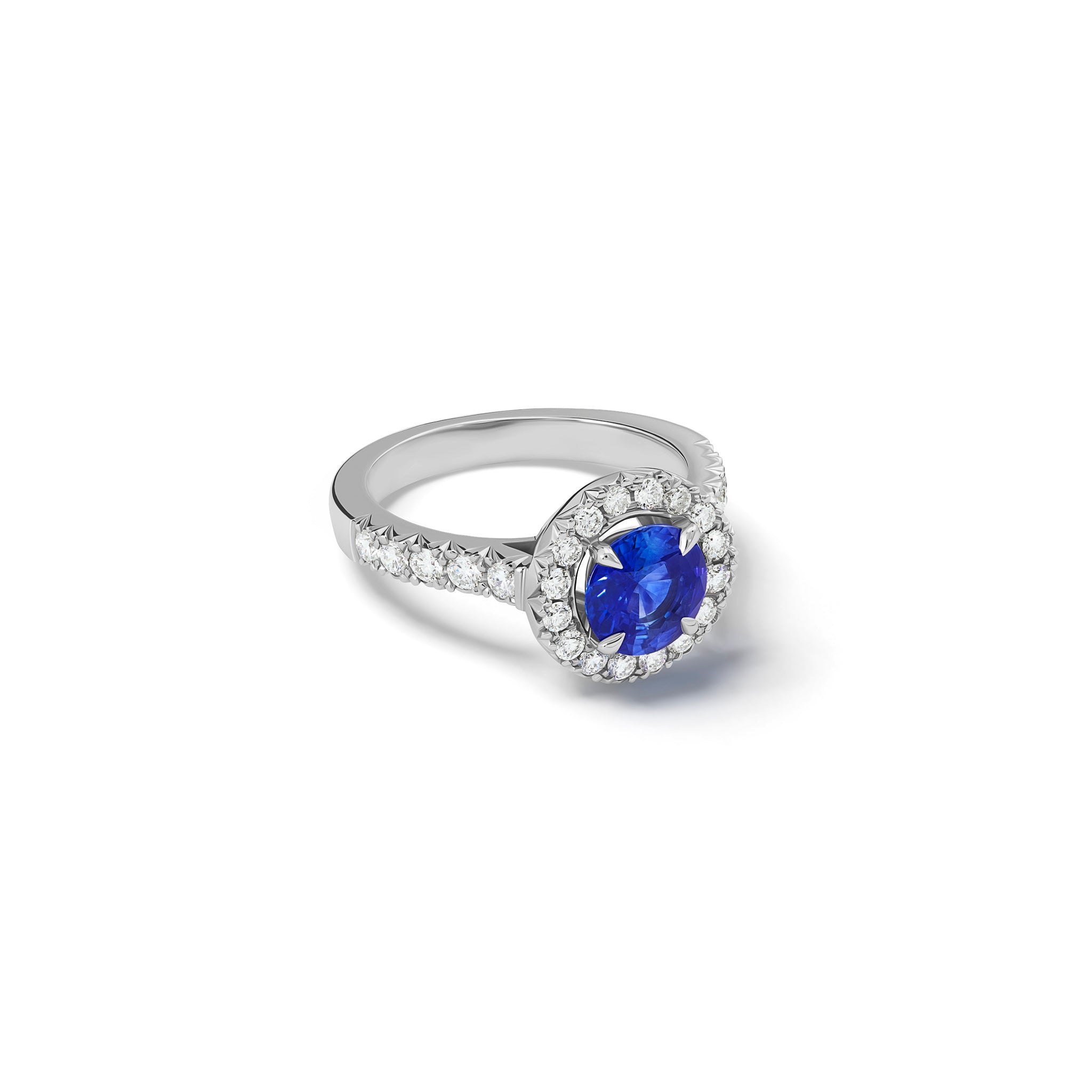 Handcrafted platinum engagement ring with a round sapphire at the centre, surrounded by smaller diamonds. The band of the engagement ring is also set with small diamonds.