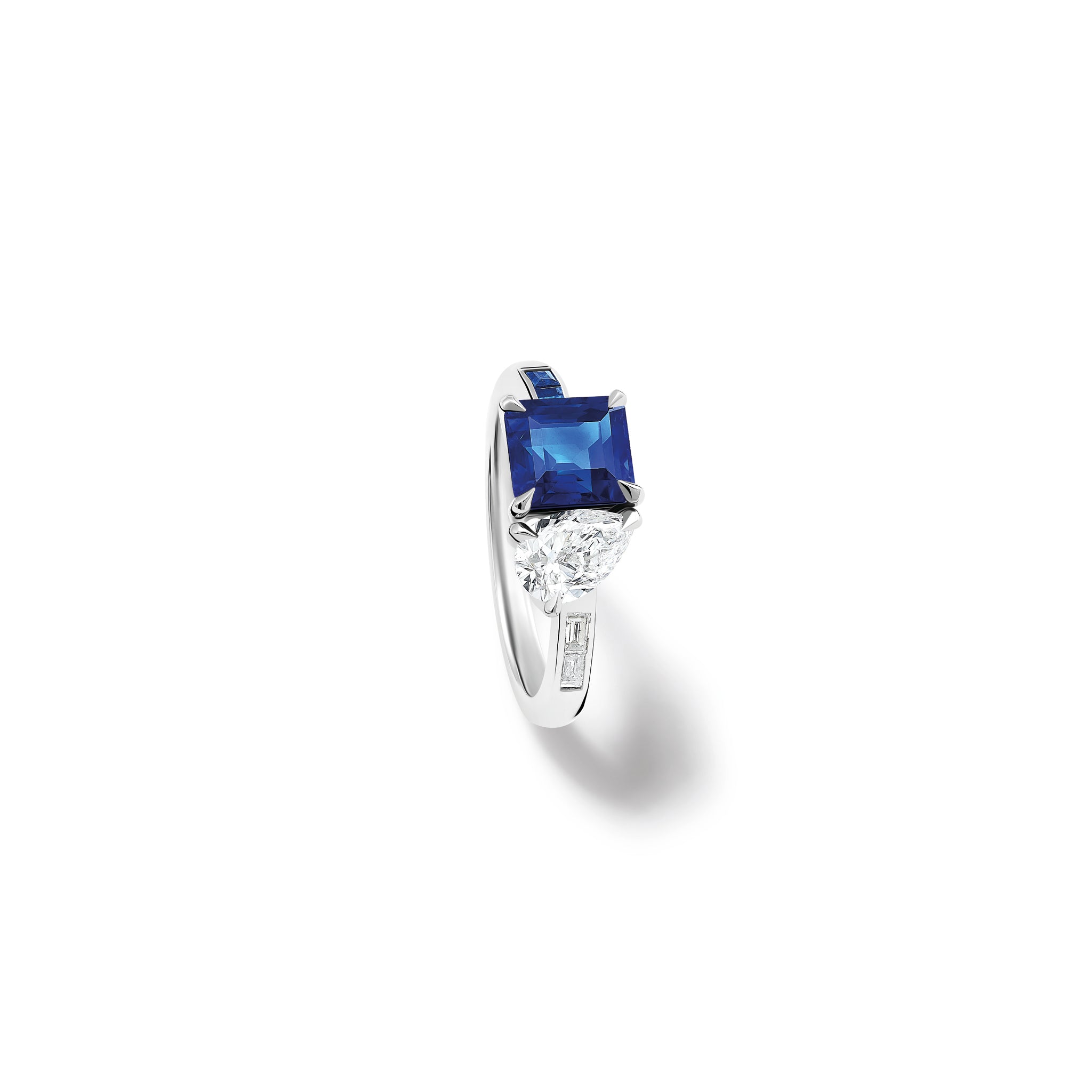 Handcrafted platinum engagement ring featuring a square-cut sapphire on the left and a teardrop-shaped diamond on the right.