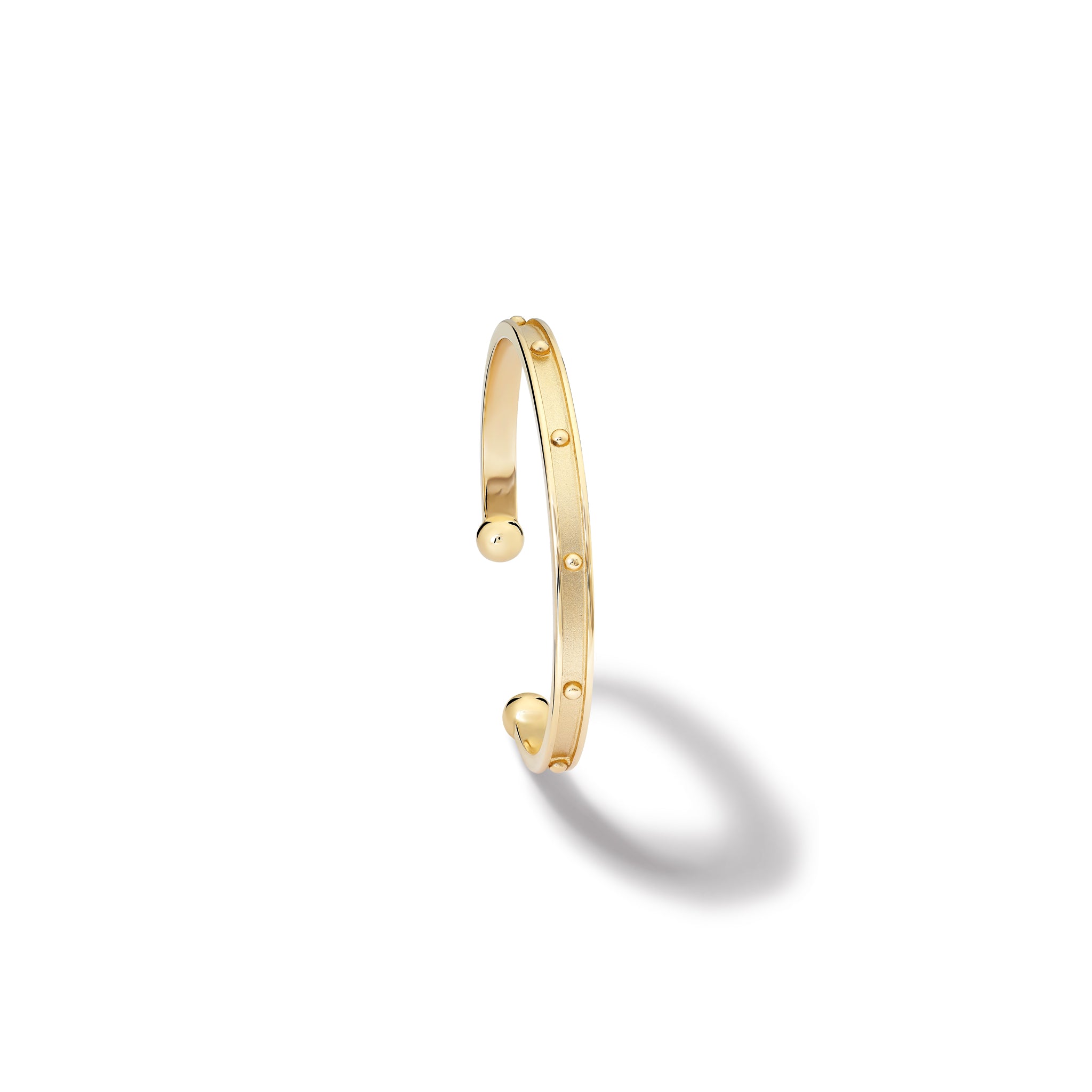 Handcrafted yellow gold bracelet cuff with evenly spaced, protruding round dots.