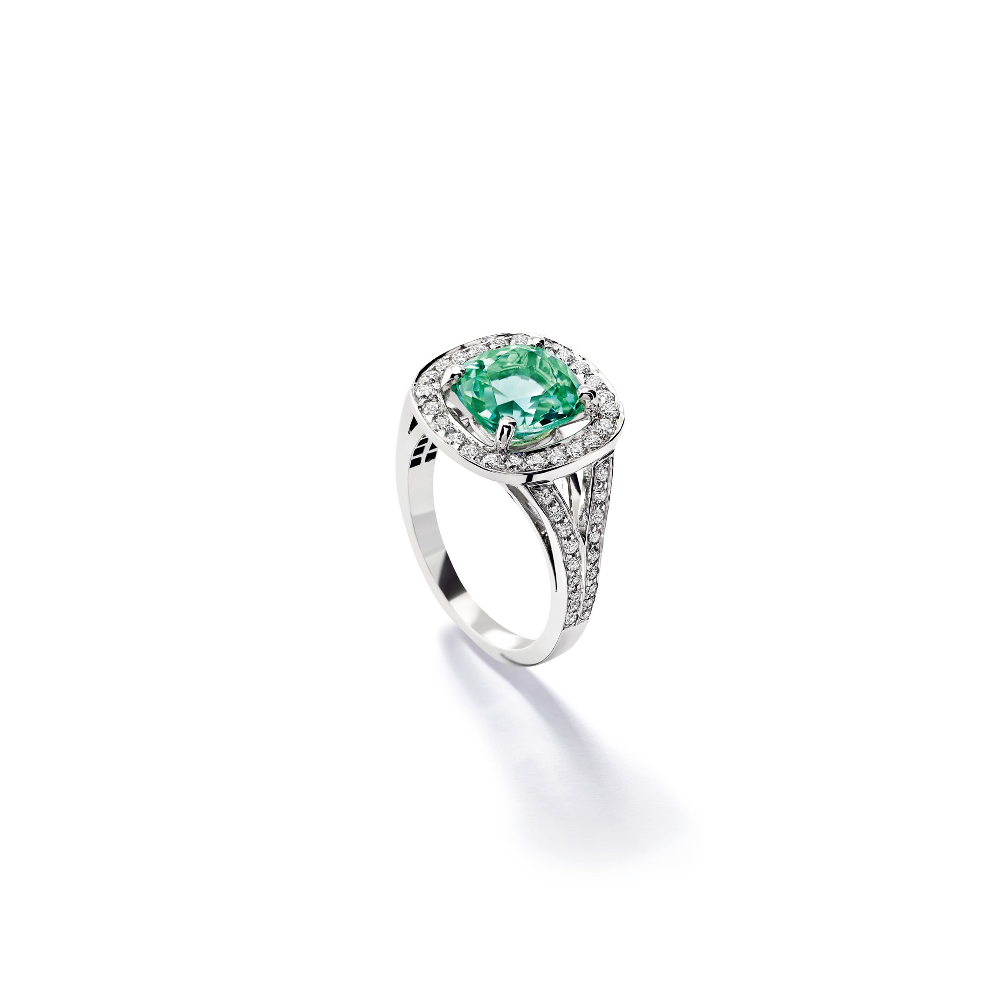 Handcrafted 18ct white gold engagement ring featuring a large, cushion-cut mint tourmaline surrounded by a halo of small diamonds and smaller diamonds embedded along the band.