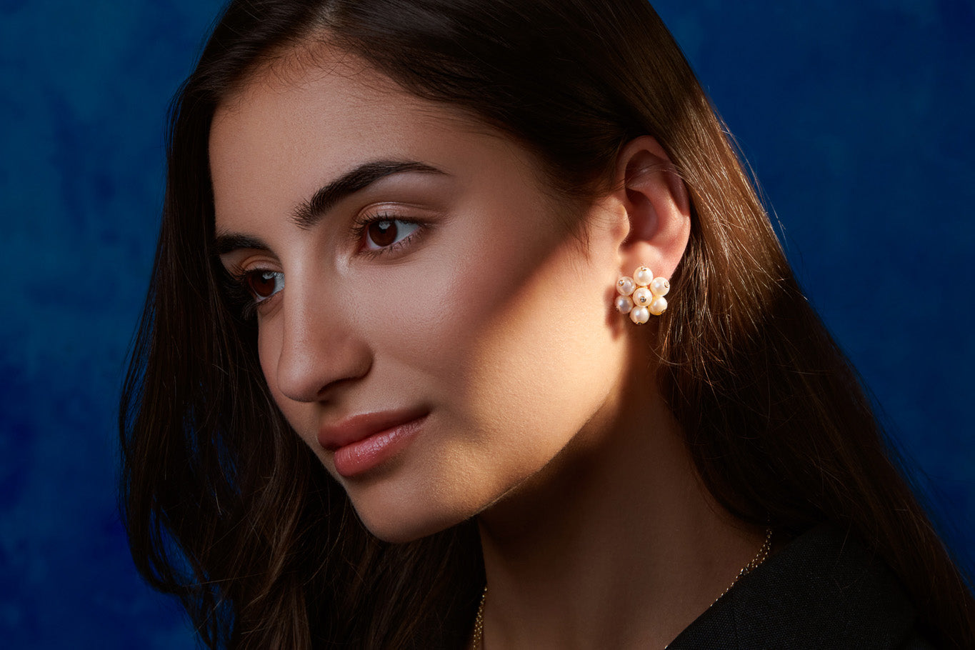 Model wearing handcrafted yellow gold cluster earrings with pearls and diamonds, inspired by the cauliflowers in Sicily.