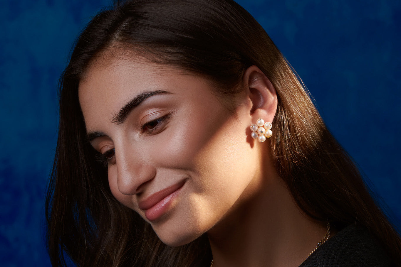 Model wearing handcrafted yellow gold earrings with pearls and diamonds featuring a cluster for a pearl wedding anniversary.