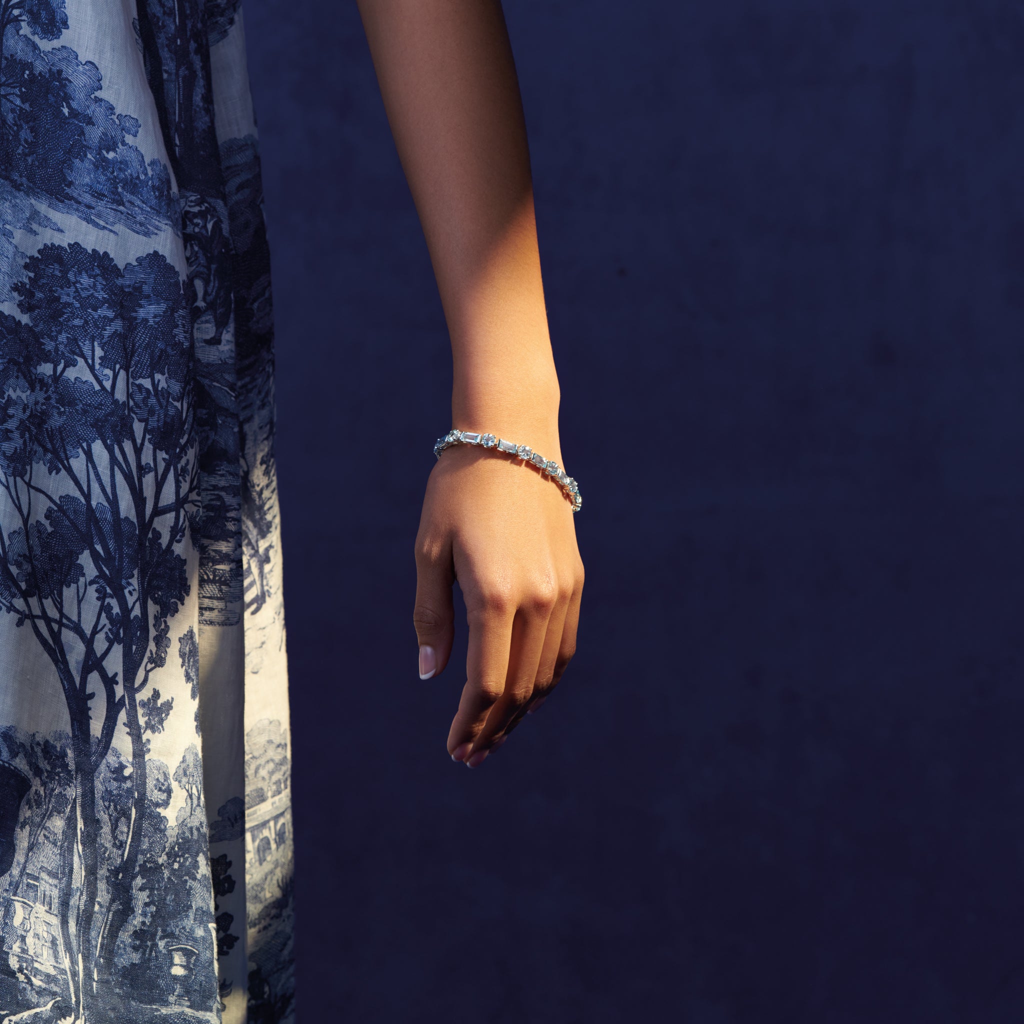 Model wearing a handcrafted 18ct white gold bracelet with baguette cut blue topaz gemstones. 
