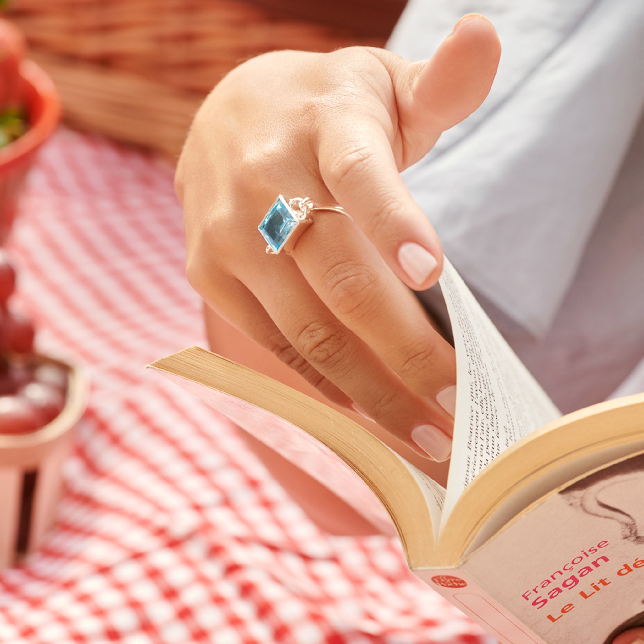 Model wearing a handcrafted sterling silver ring featuring a central blue topaz, birthstone of November.