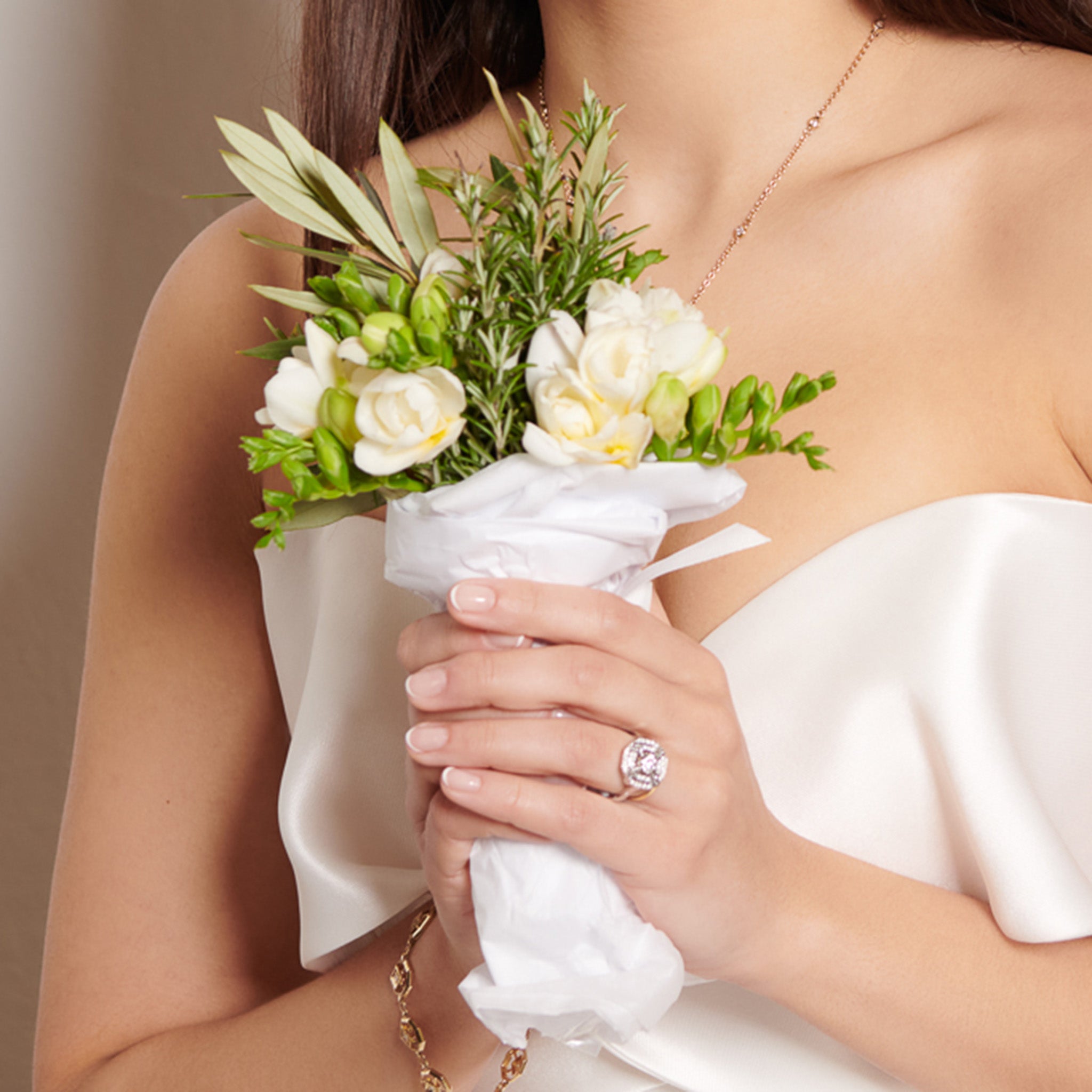 Model wearing a 18ct white gold engagement ring featuring a central square-cut central diamond, surrounded by two tiers of small round diamonds set in a hexagonal pattern.