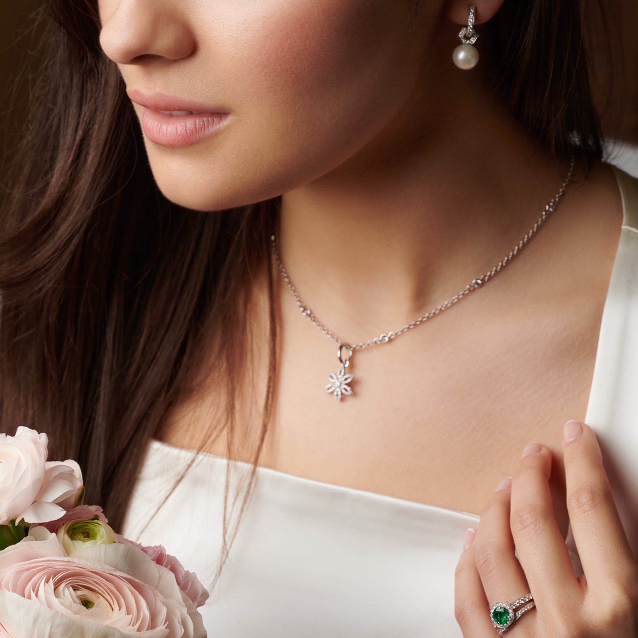 Model wearing a handcrafted 18ct white gold flower necklace pendant with diamond pavé and central diamond, birthstone of April.