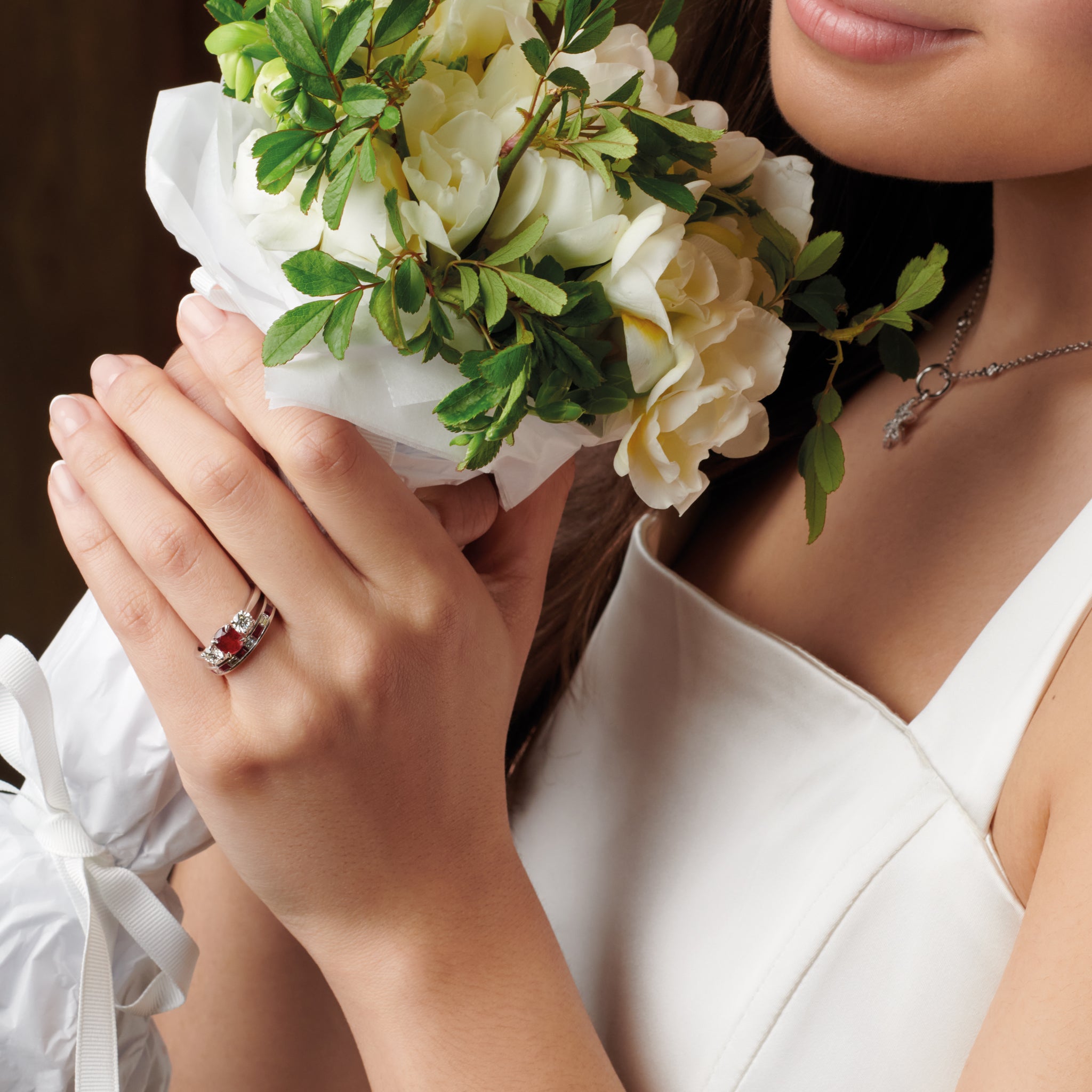 Model wearing a handcrafted 18ct white gold engagement ring featuring a large, oval ruby at its centre, surrounded by two smaller teardrop-shaped white diamonds.