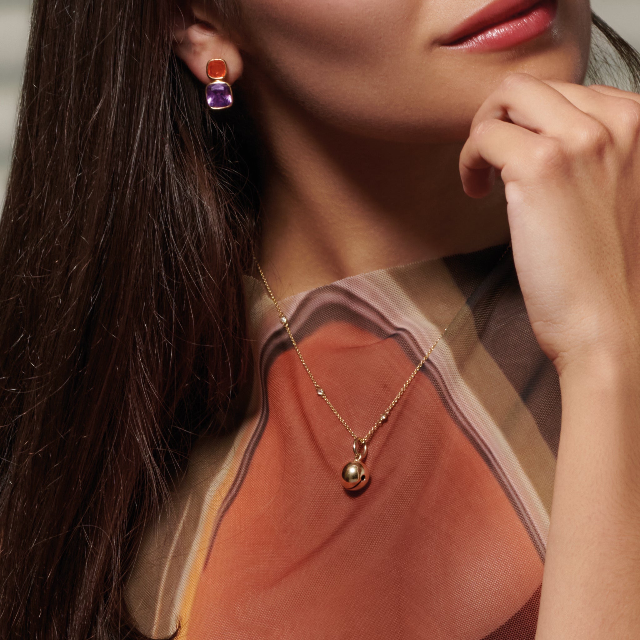 Model wearing a handcrafted sterling silver necklace pendant designed in the shape of a bell.