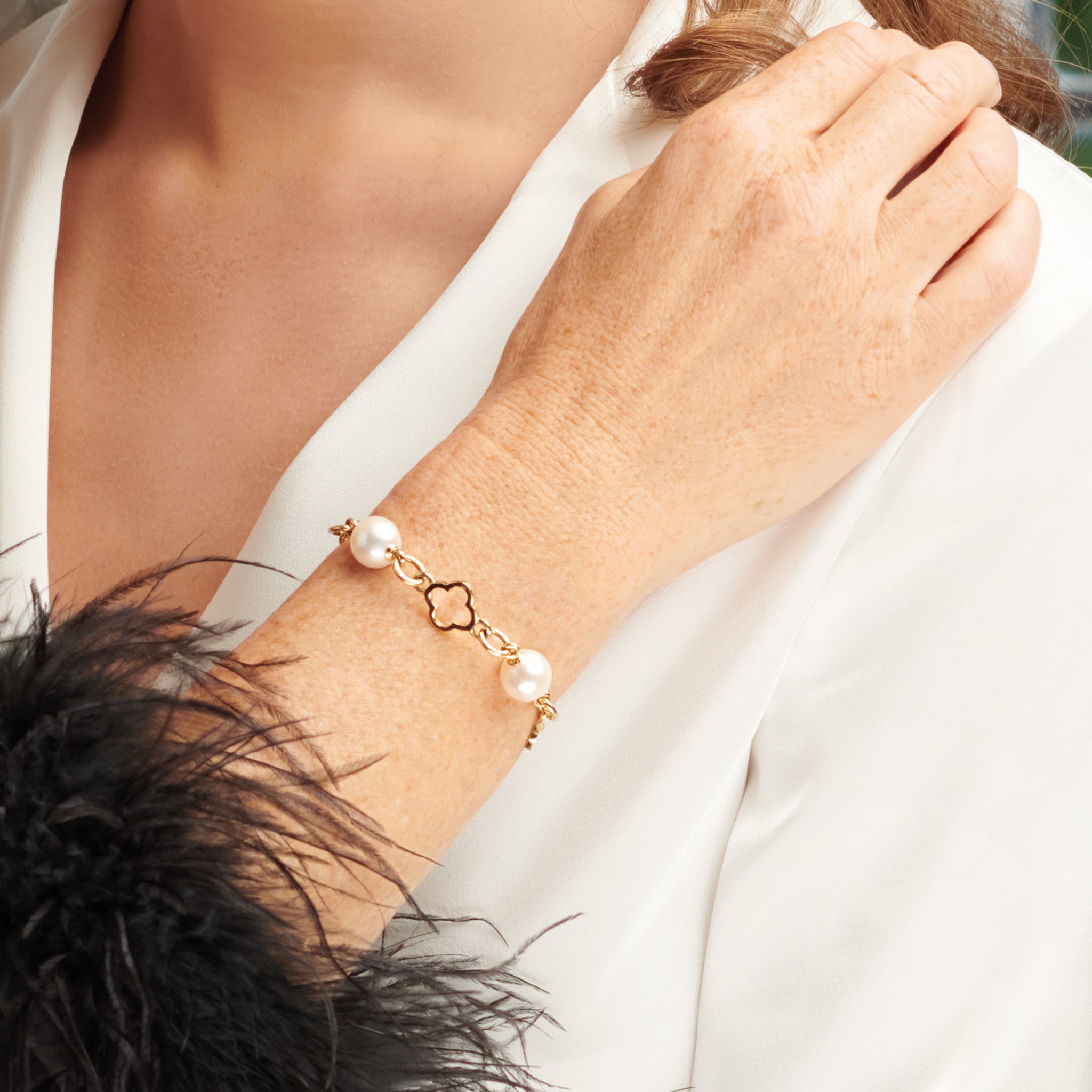 Model wearing a handcrafted yellow gold bracelet with star-shaped links, spaced with pearls, birthstone of June.