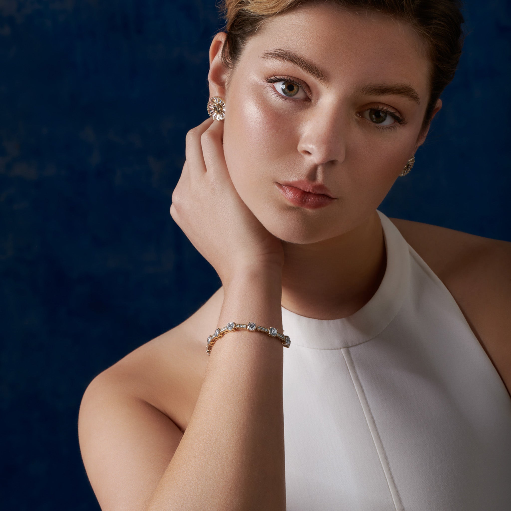 Model wearing a handcrafted 18ct yellow gold bracelet with baguette cut diamonds. 
