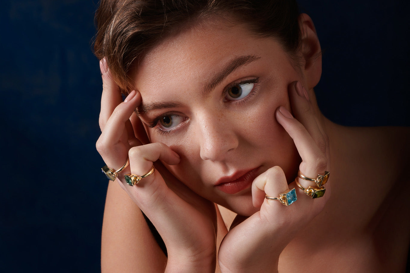 Model wearing handcrafted yellow gold rings featuring baguette cut peridot gemstones, birthstone of August.