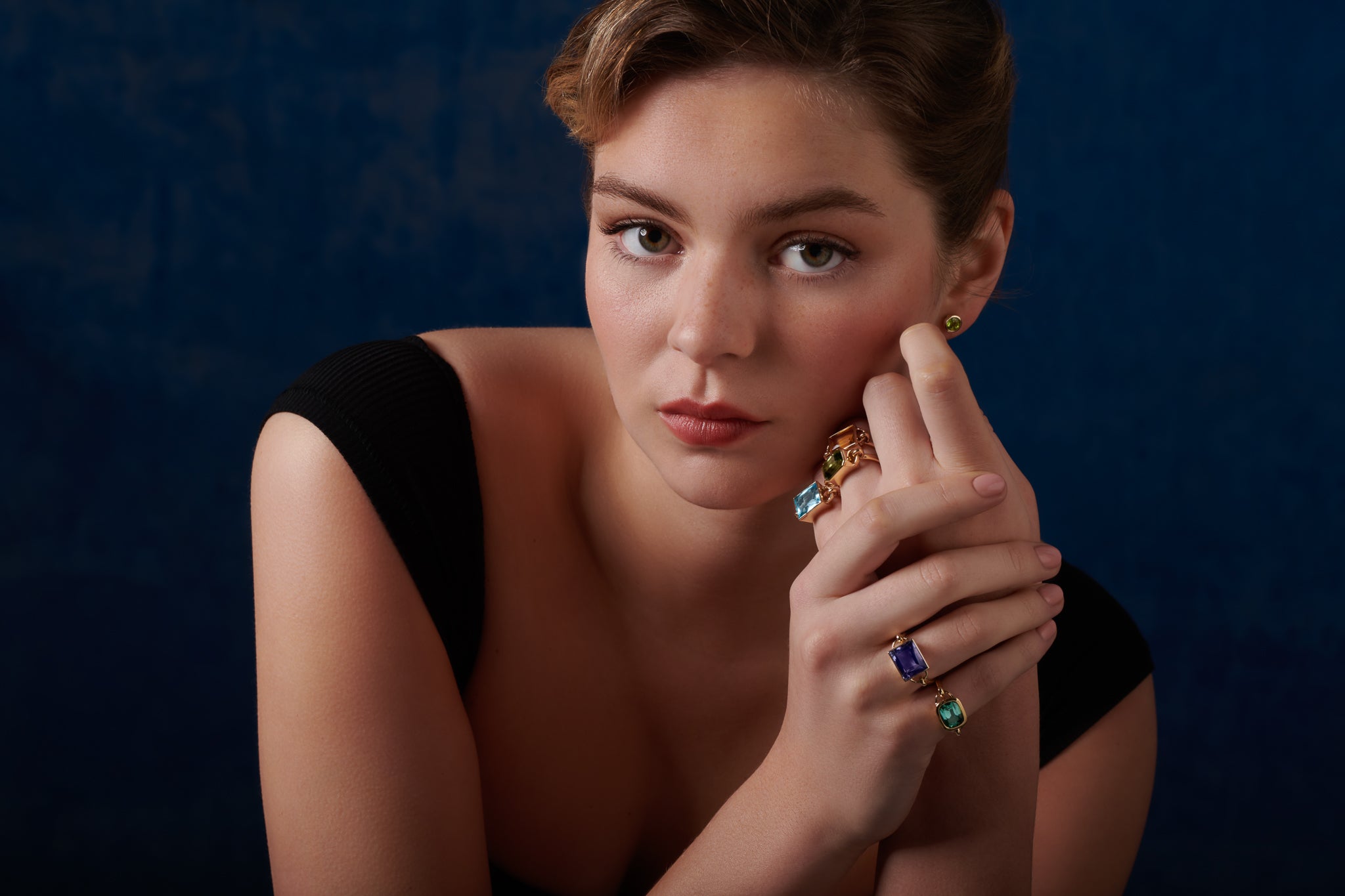 Model wearing handcrafted yellow gold rings featuring different baguette cut precious gemstones.