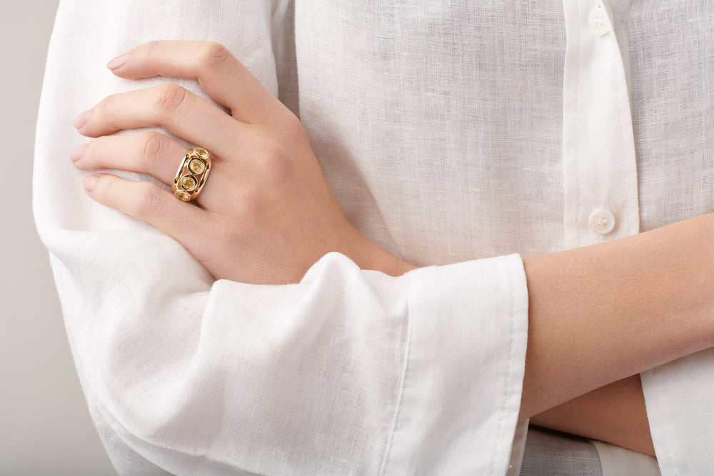 Model wearing a handcrafted yellow gold ring featuring four round citrines, birthstone of November.