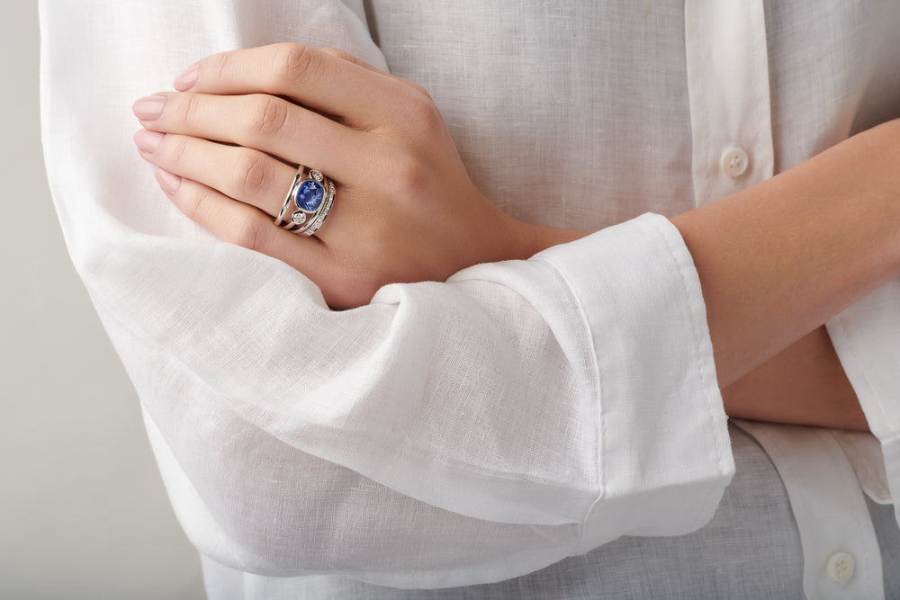 Model wearing a handcrafted white gold ring featuring a facetted sapphire, birthstone of September.