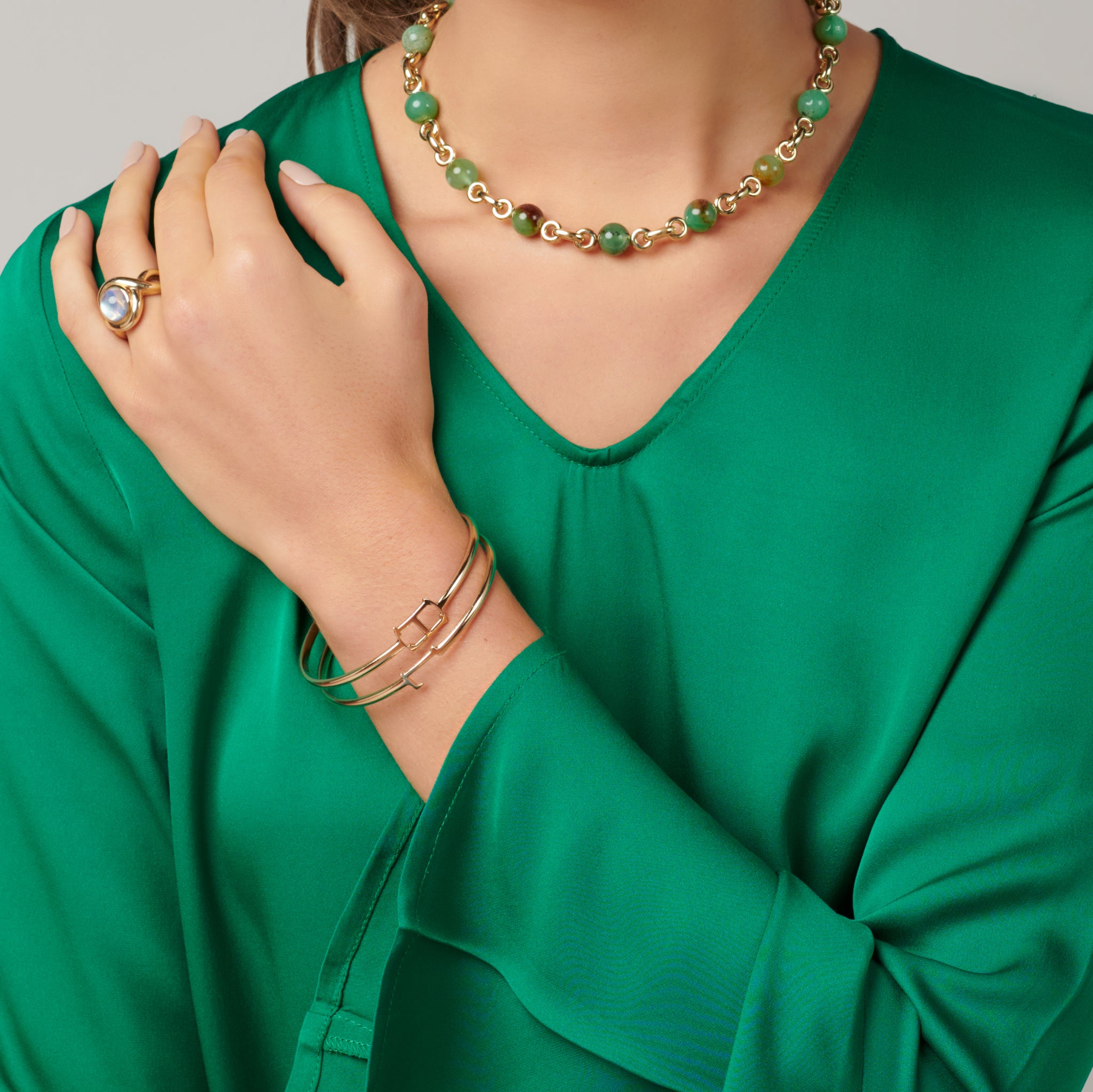 Model wearing a handcrafted sterling silver bangle with a central silver letter accent.