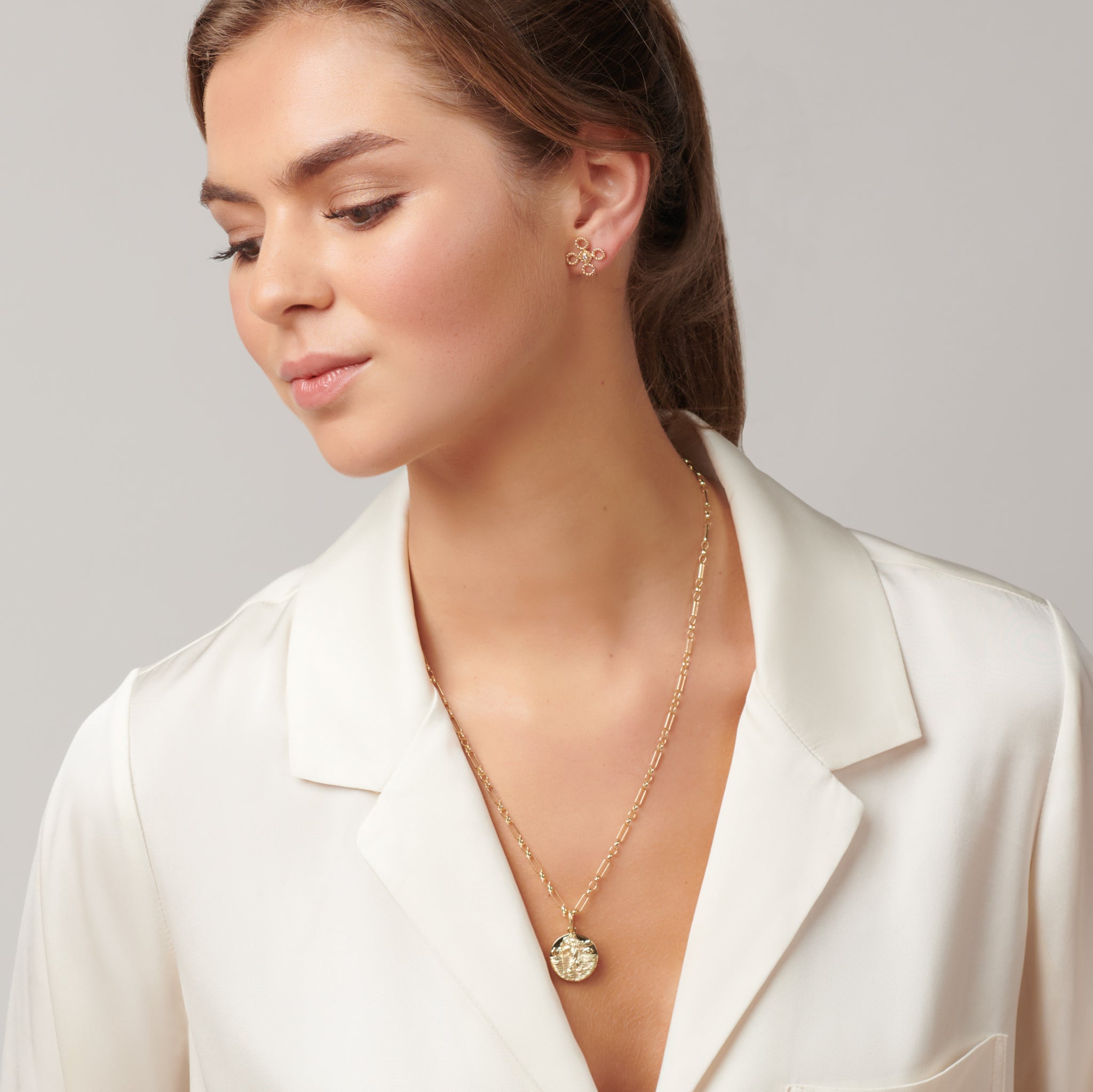 Model wearing a handcrafted round yellow gold necklace pendant featuring an engraving of Saint Christopher on a chain. 