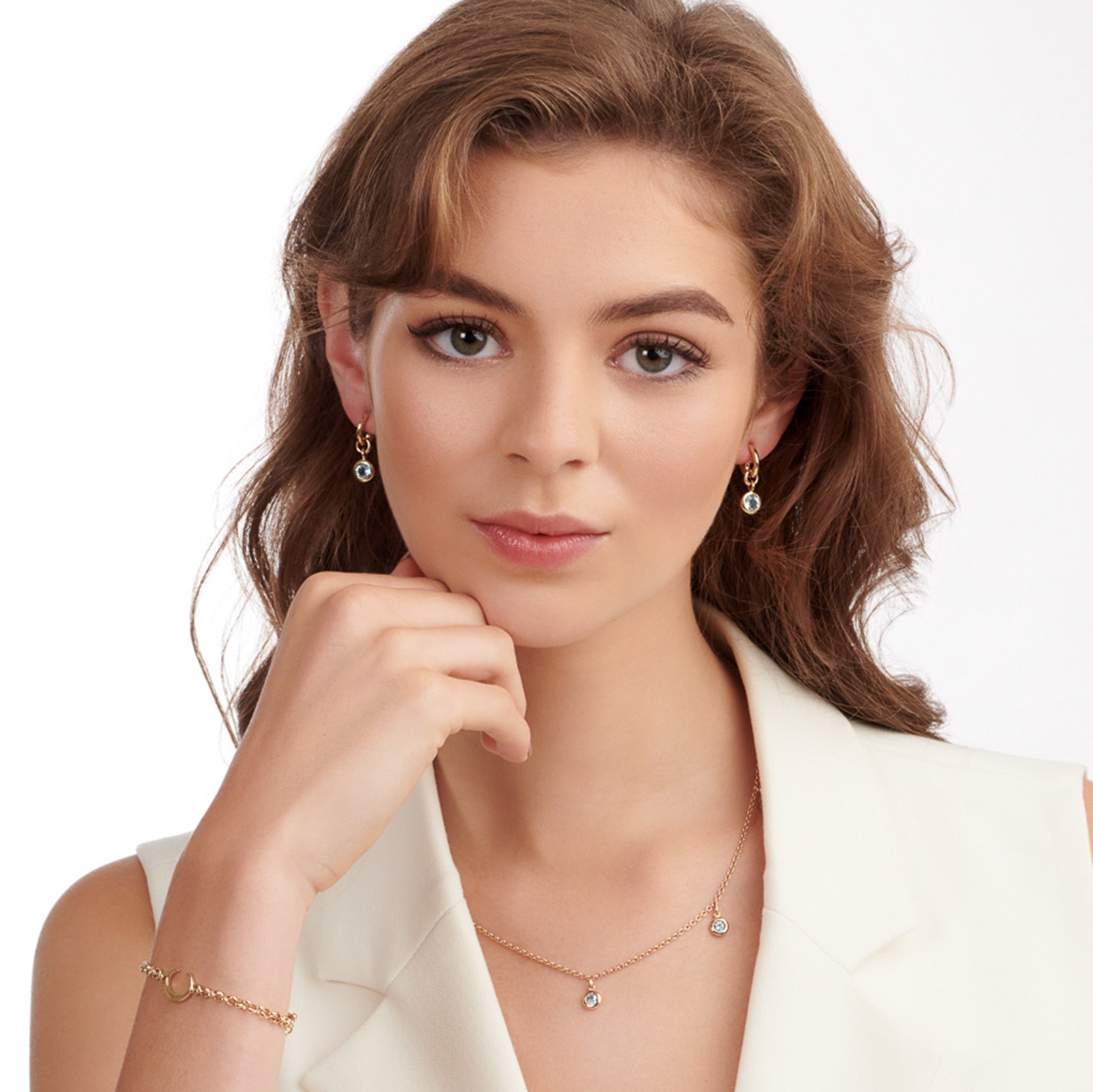 Model wearing handcrafted earring drops in precious metal with round precious stones.