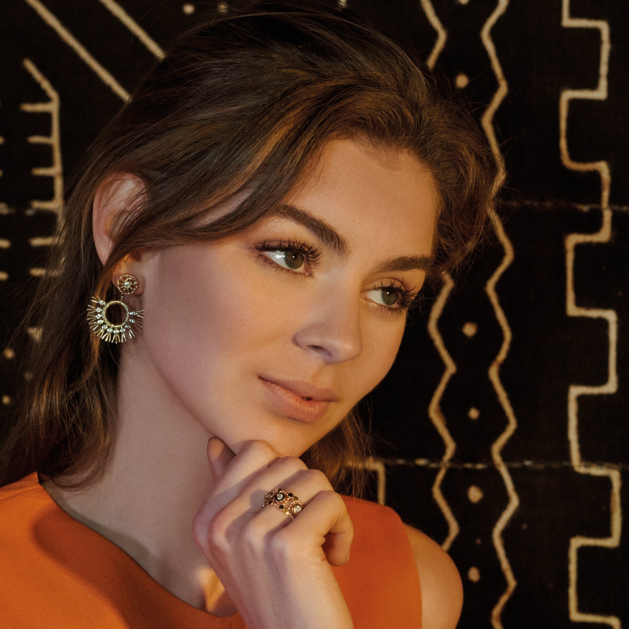 Model wearing handcrafted yellow gold earrings with diamonds in the shape of dried palm fronds from Morocco.
