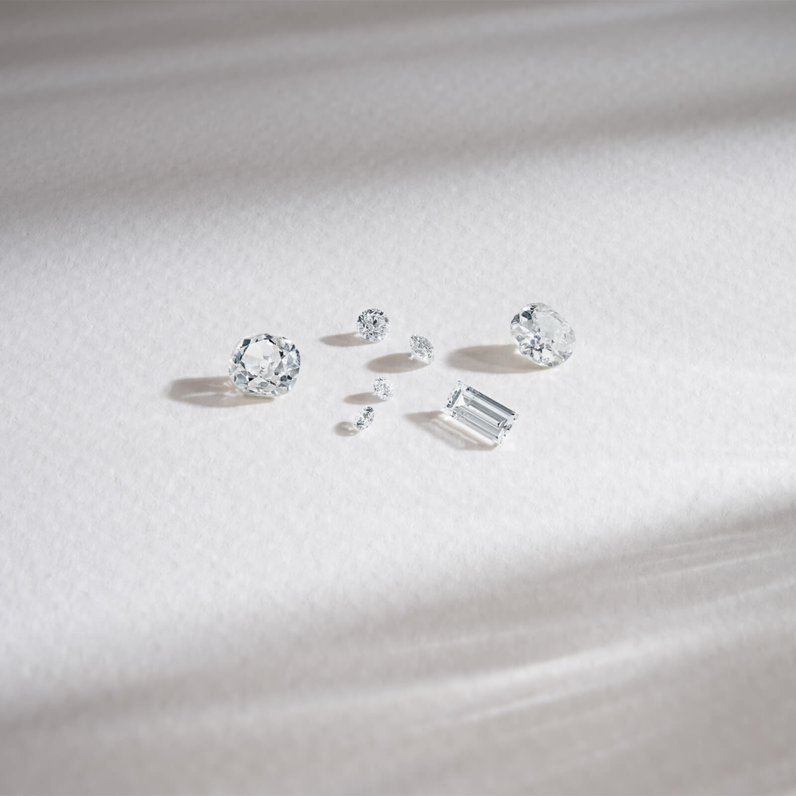 Various sized diamonds resting on a white surface.