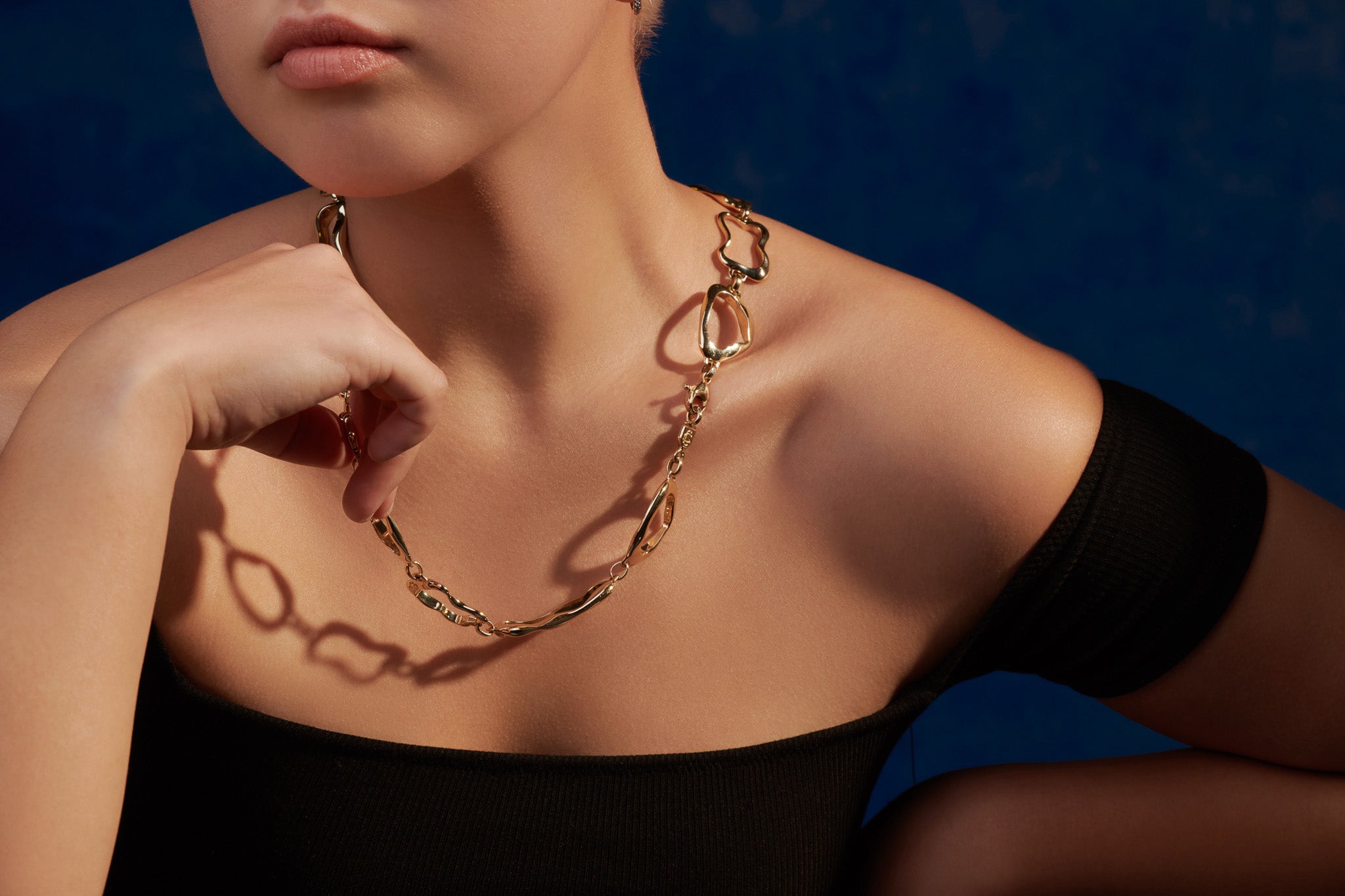 Model wearing a handcrafted yellow gold necklace featuring different shapes of pastries.