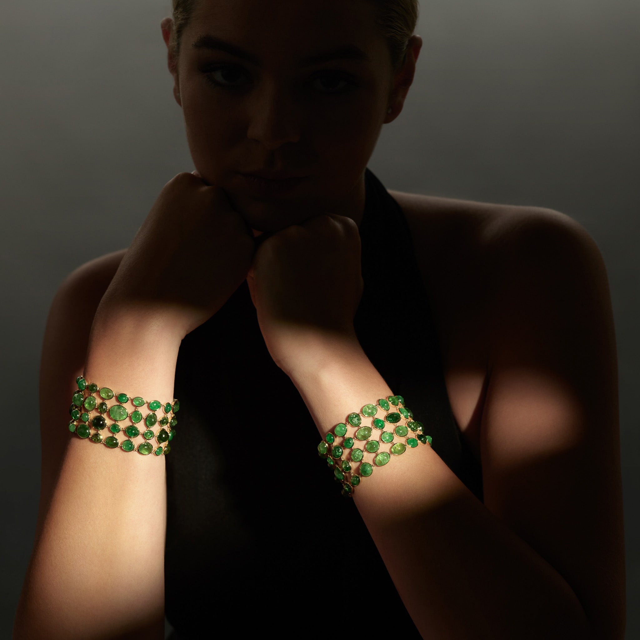 Model wearing a handcrafted 18ct yellow gold bracelet with rare cabochon Tsavorite garnets. 