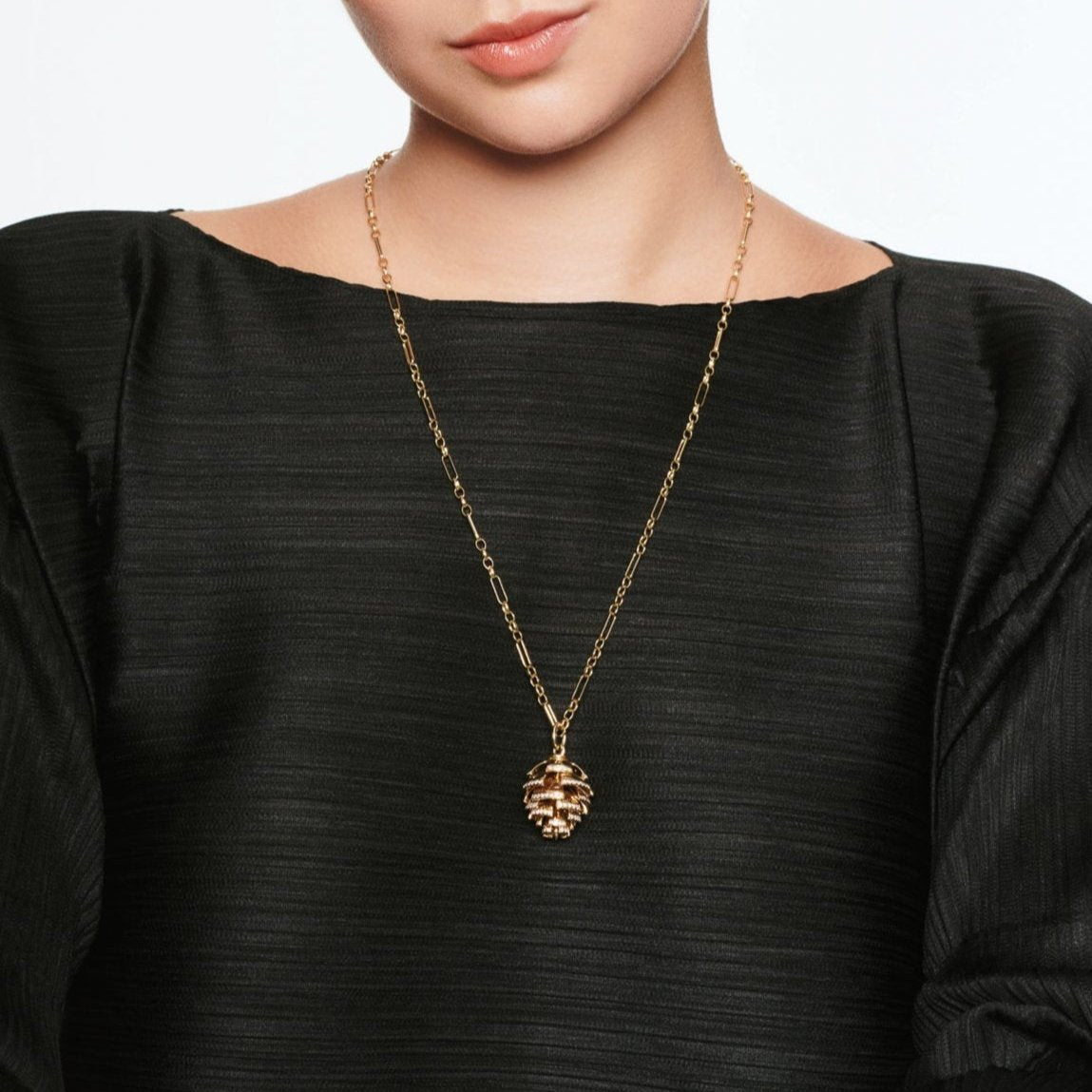 Model wearing a handcrafted yellow gold fir cone shaped necklace pendant with diamonds.