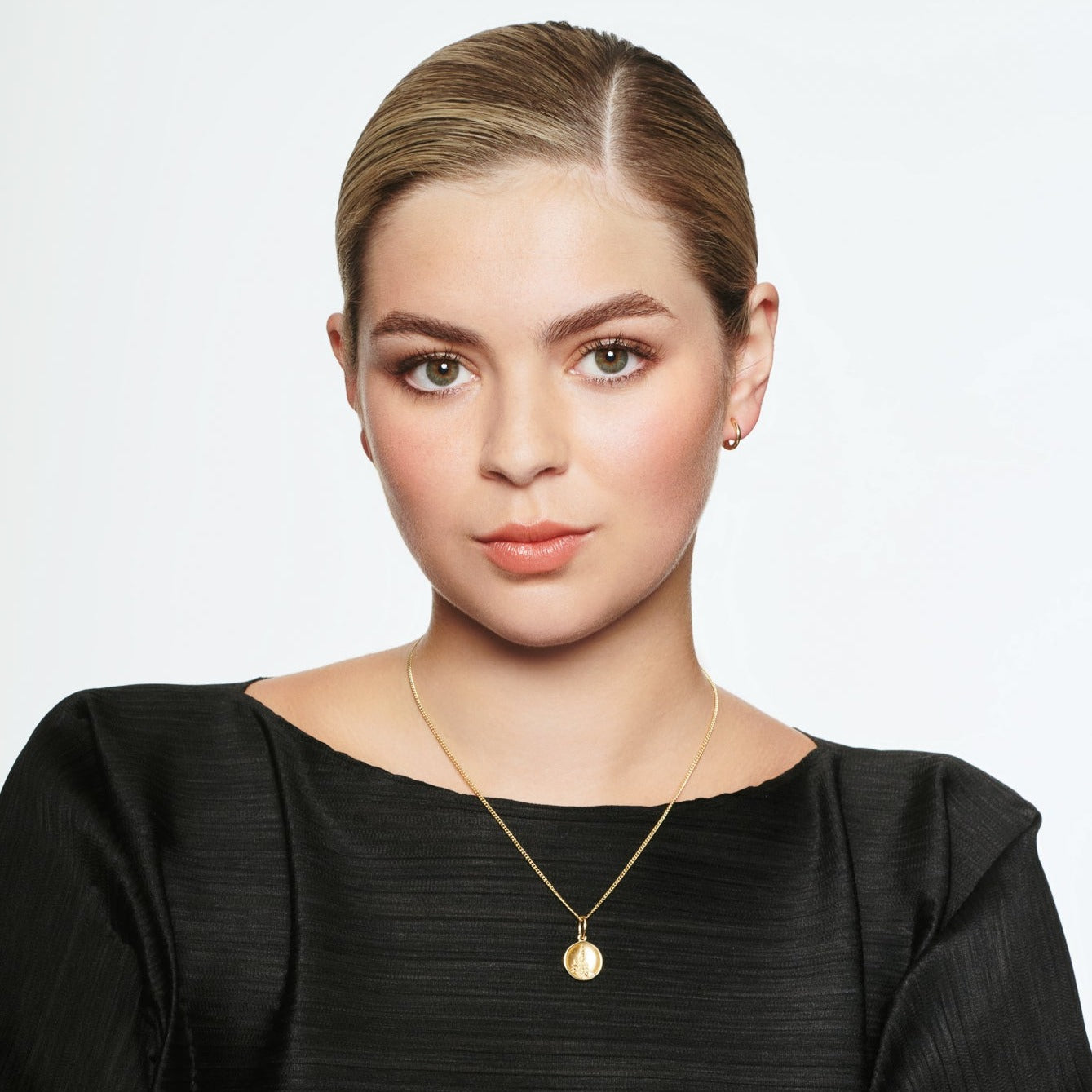 Model wearing a handcrafted yellow gold necklace pendant 'en relief' with the culture from France.
