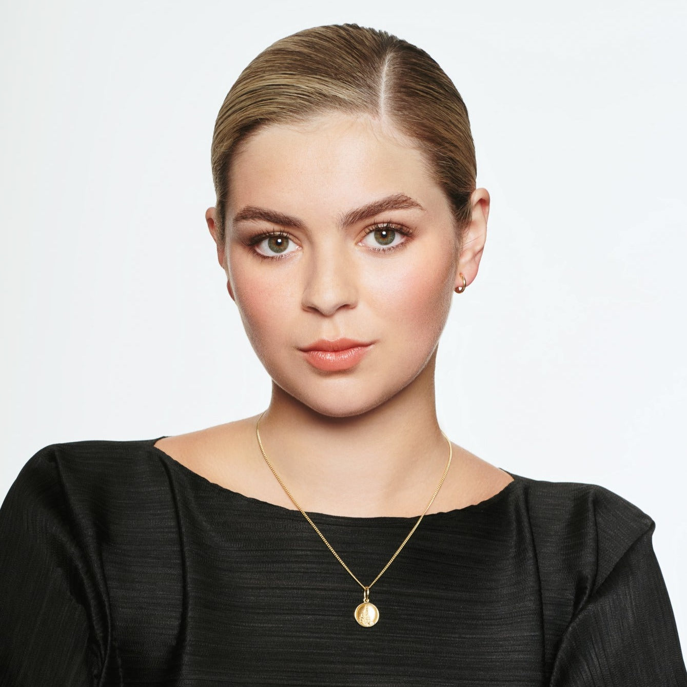 Model wearing a handcrafted round yellow gold necklace pendant featuring an engraving of Mont Saint-Michel Abbey in France on a gold chain.