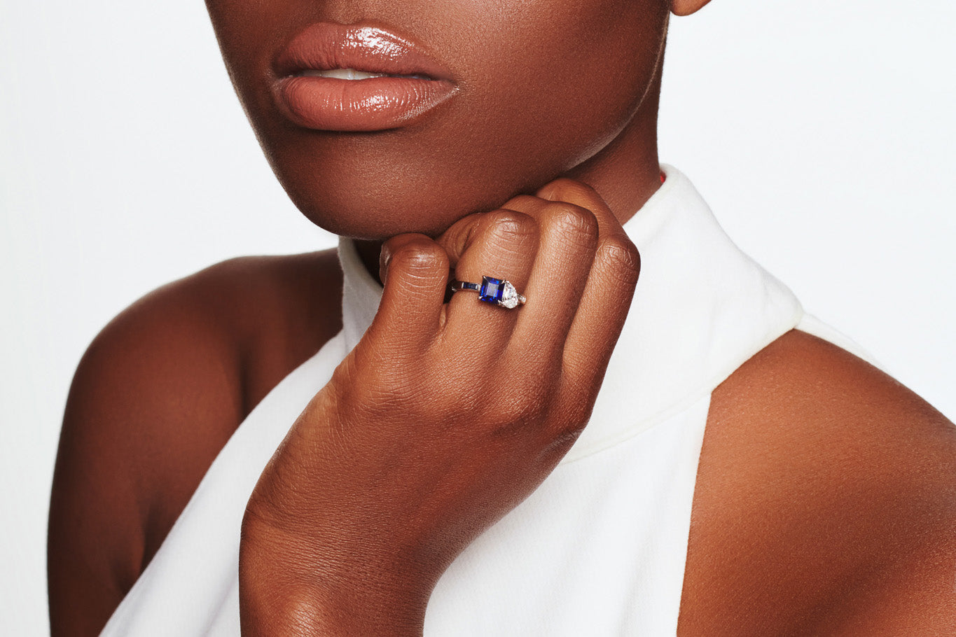 Model wearing a handcrafted 18ct white gold ring featuring an emerald cut sapphire and a pear shaped diamond.