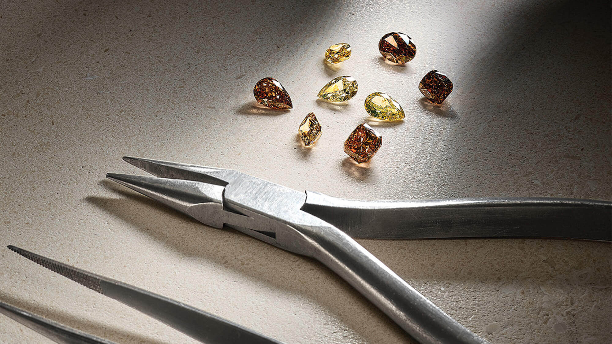 Jewellery tools arranged alongside brown and yellow precious gemstones