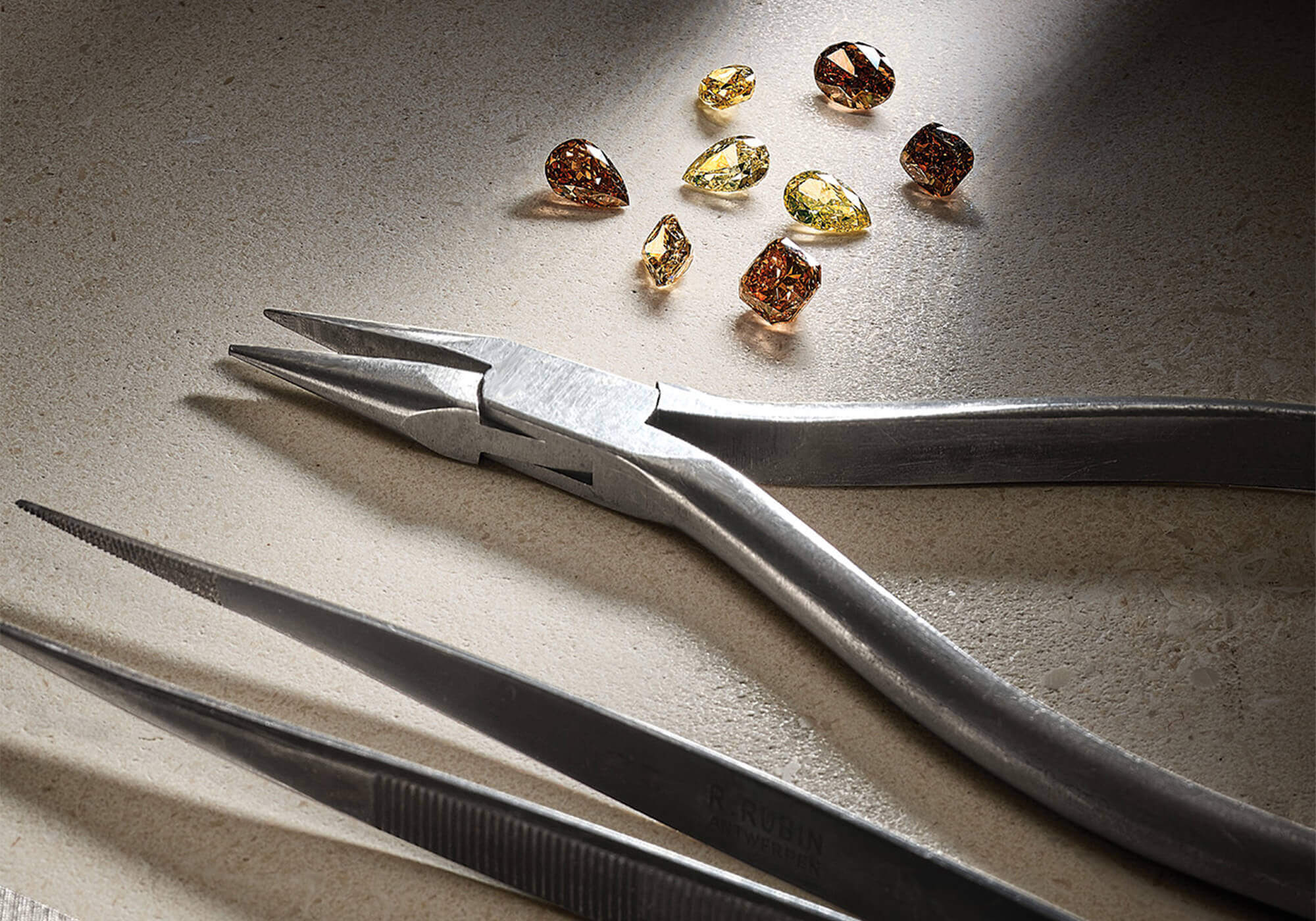 Jewellery tools next to brown and yellow precious stones.