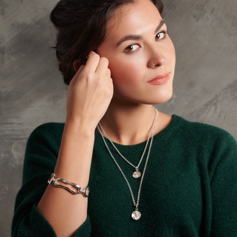 Model wearing a handcrafted sterling silver bracelet featuring the outlines of french paisteries: �clair, canel�, pain au chocolat and croissant.