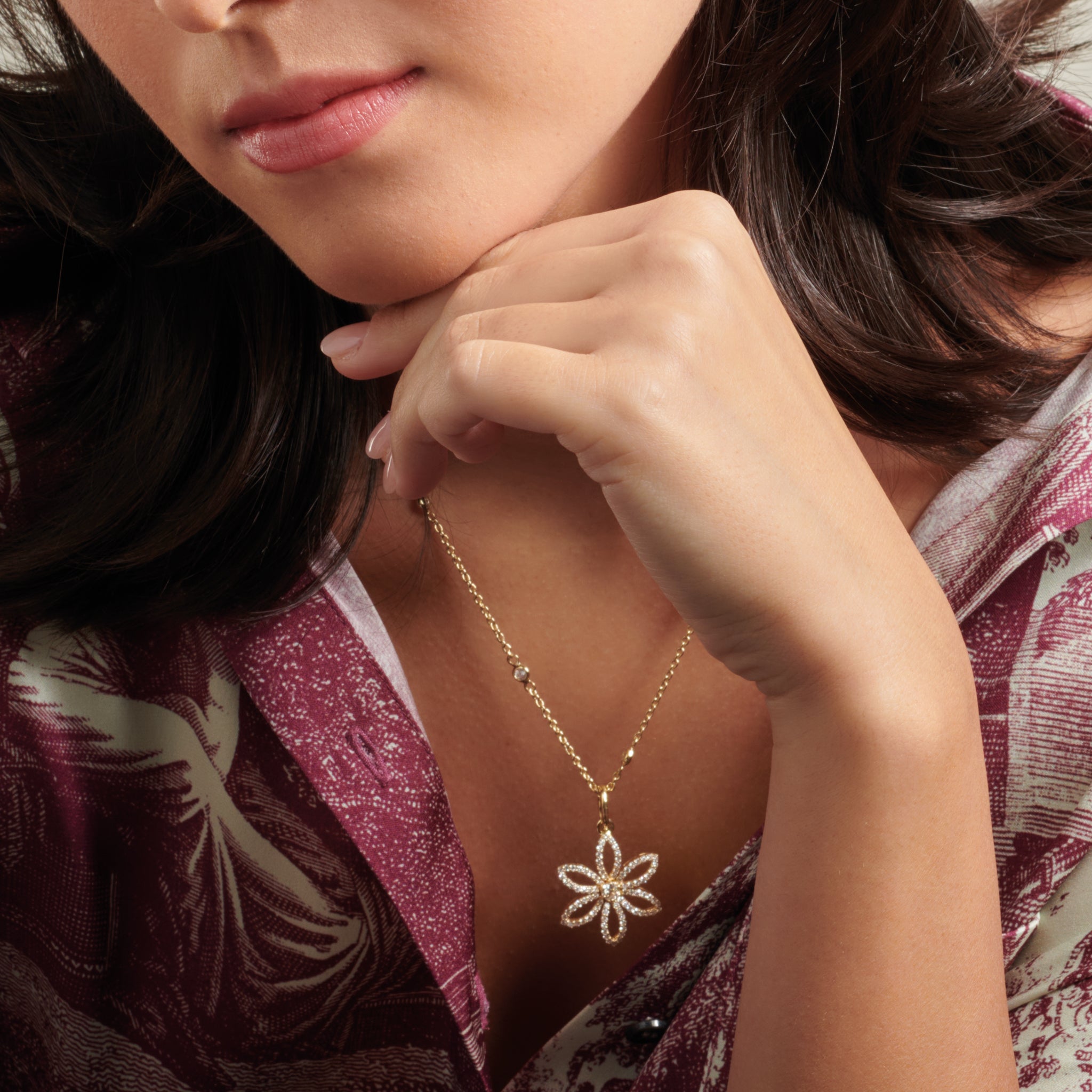 Model wearing a handcrafted flower necklace pendant in precious metal with a central precious stone.