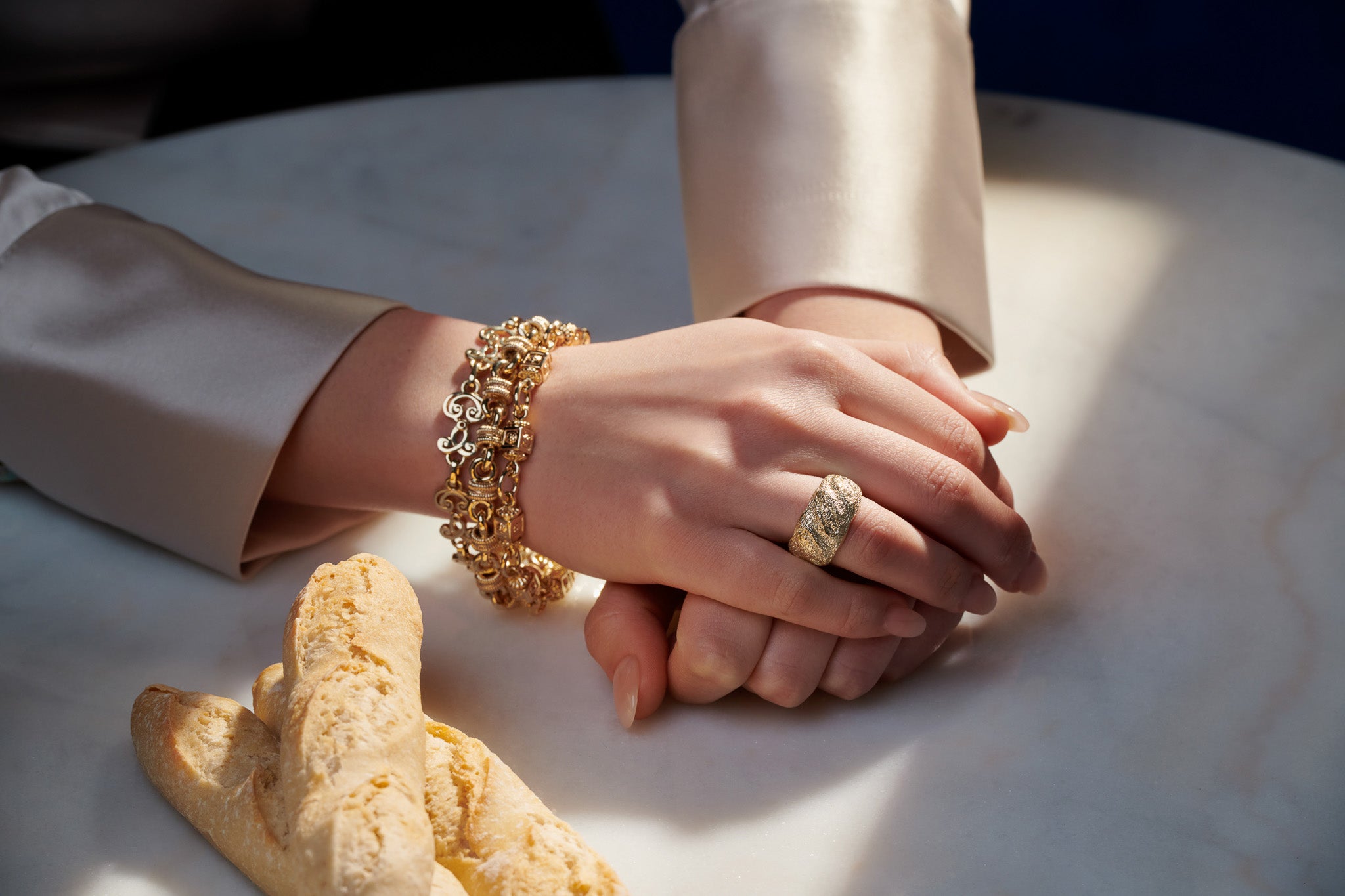 Model wearing handcrafted yellow gold bracelets stacked with different links and designs.