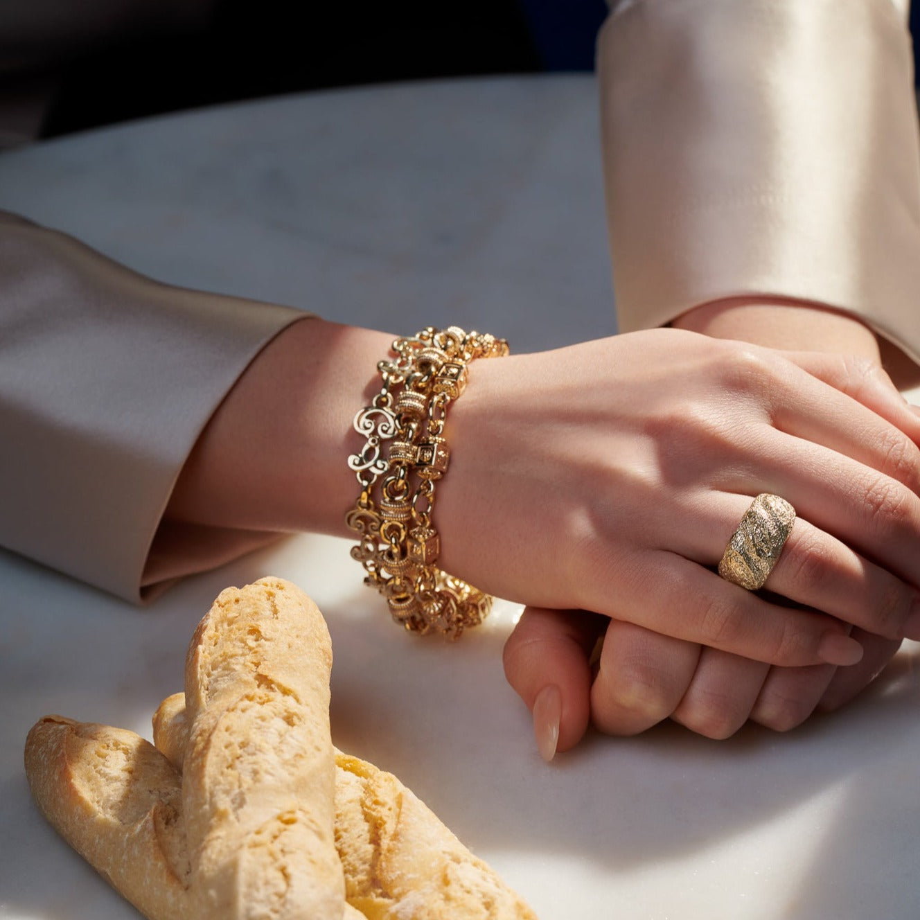 Model wearing a handcrafted yellow gold bracelet featuring a design of interlocking circles, each connected through intricately detailed squares.