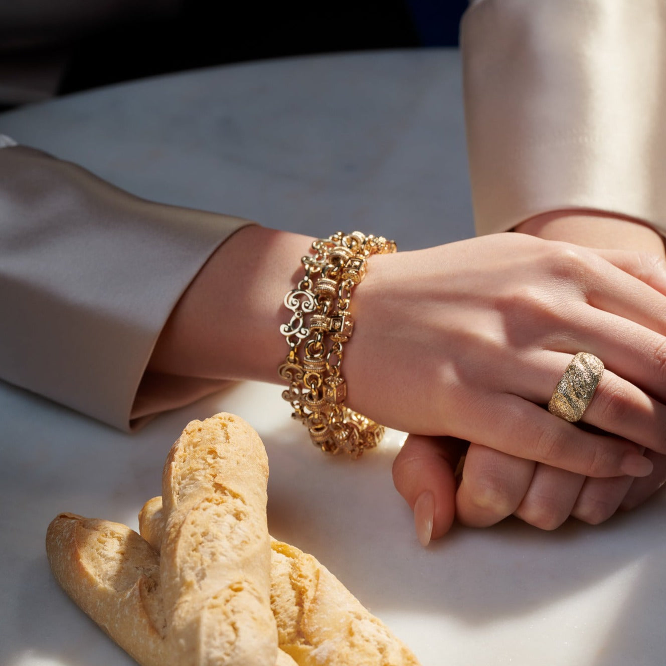 Model wearing handcrafted yellow gold bracelets featuring ironwork motifs from the stables in France.