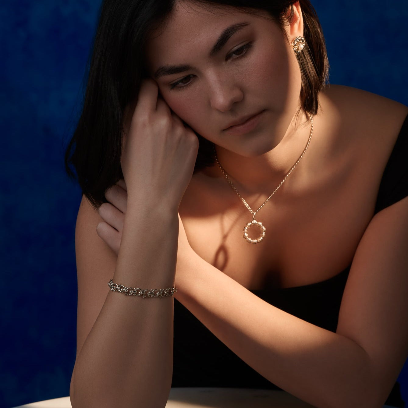 Model wearing a handcrafted yellow gold bracelet with links and small beads.