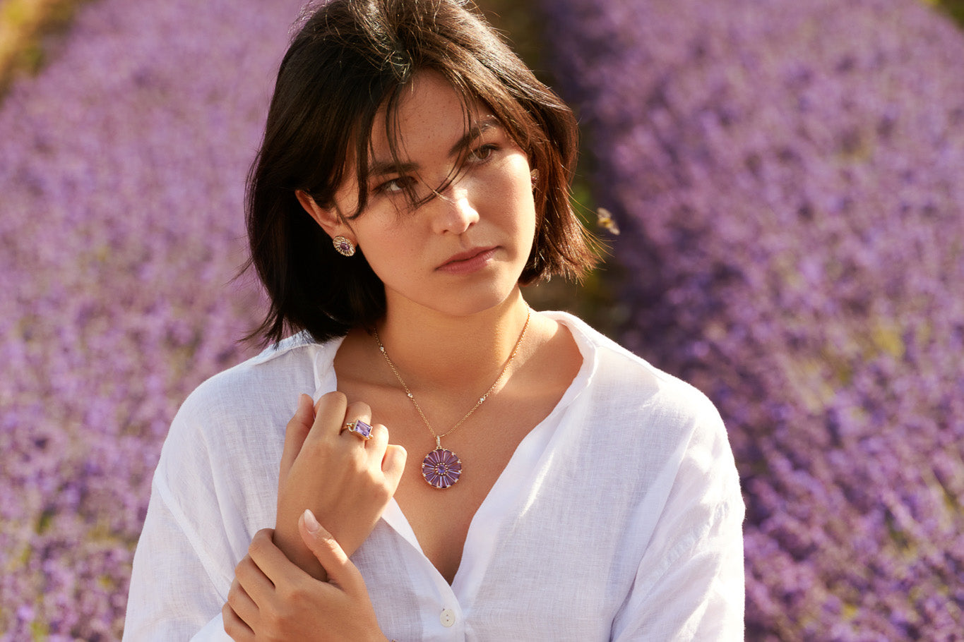 Model wearing handcrafted yellow gold jewellery featuring precious amethyst gemstones in a lavender field.