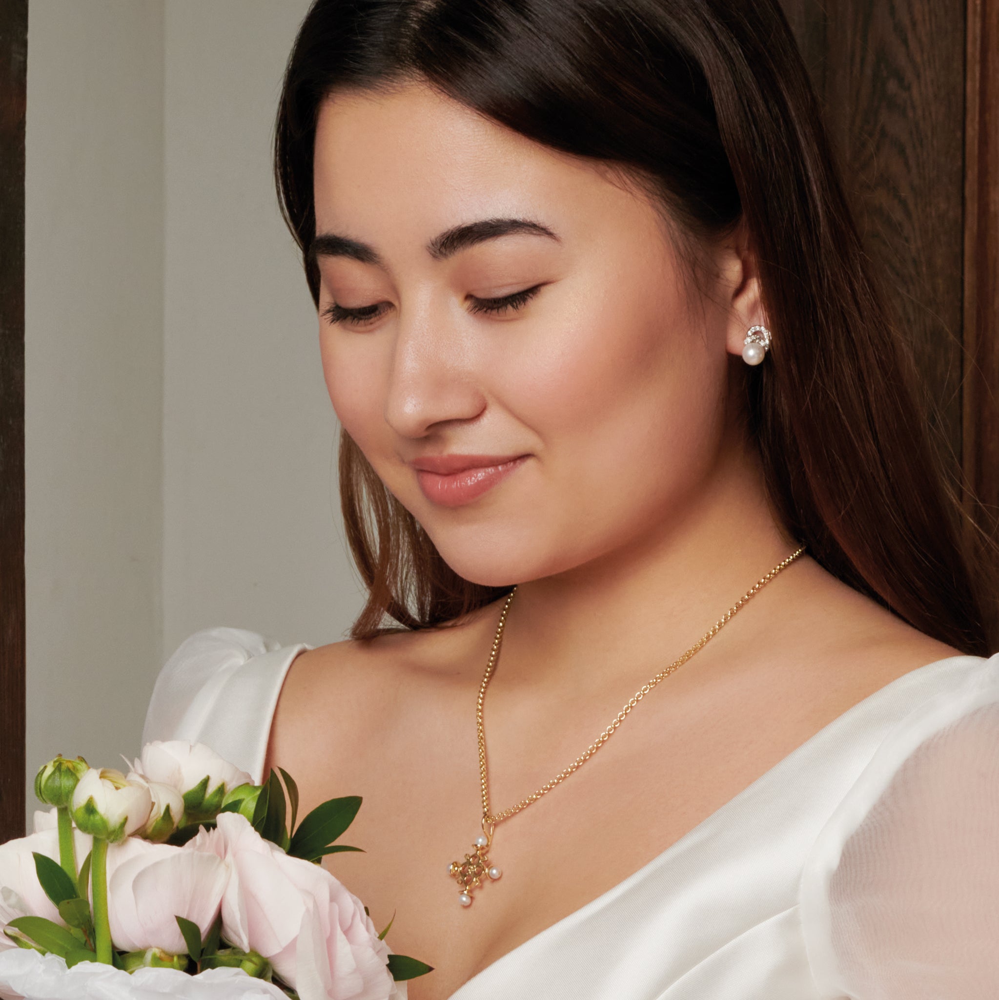 Model wearing a handcrafted cross necklace pendant in precious metal with precious stone.