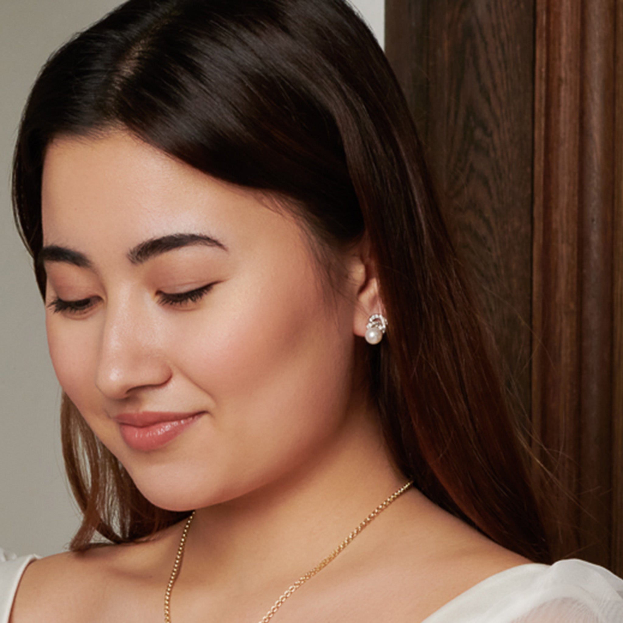 Model wearing handcrafted 18ct white gold earrings with a pearl and diamond pavé. 