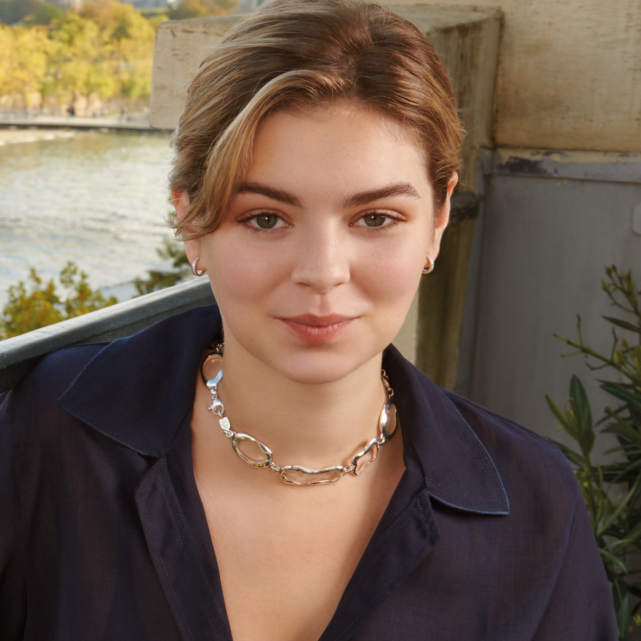 Model wearing a handcrafted sterling silver necklace featuring the outlines of french pastries: éclair, canelé, pain au chocolat and croissant. 