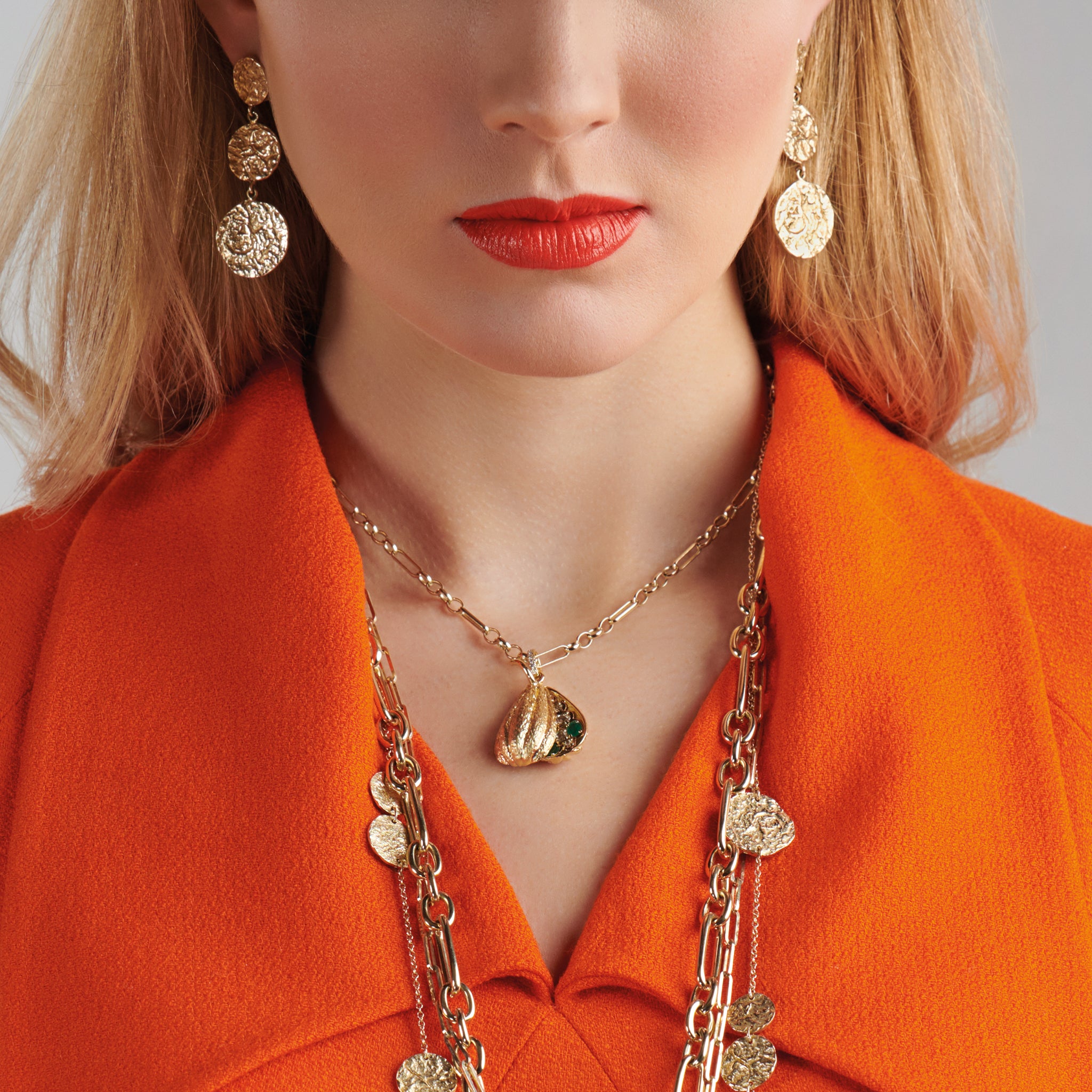 Model wearing a handcrafted necklace pendant shaped like cocoa pod in precious metal.