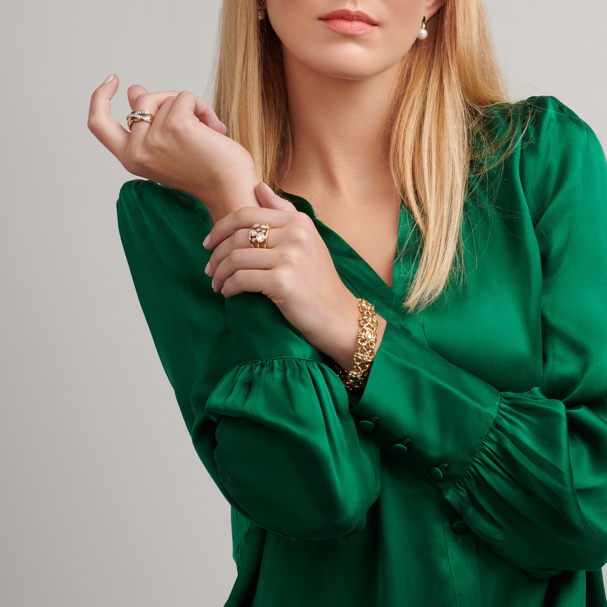 Model wearing a handcrafted 18ct yellow gold bracelet with bold curls of intertwined golden strands, accented with gold and square-cut diamonds.