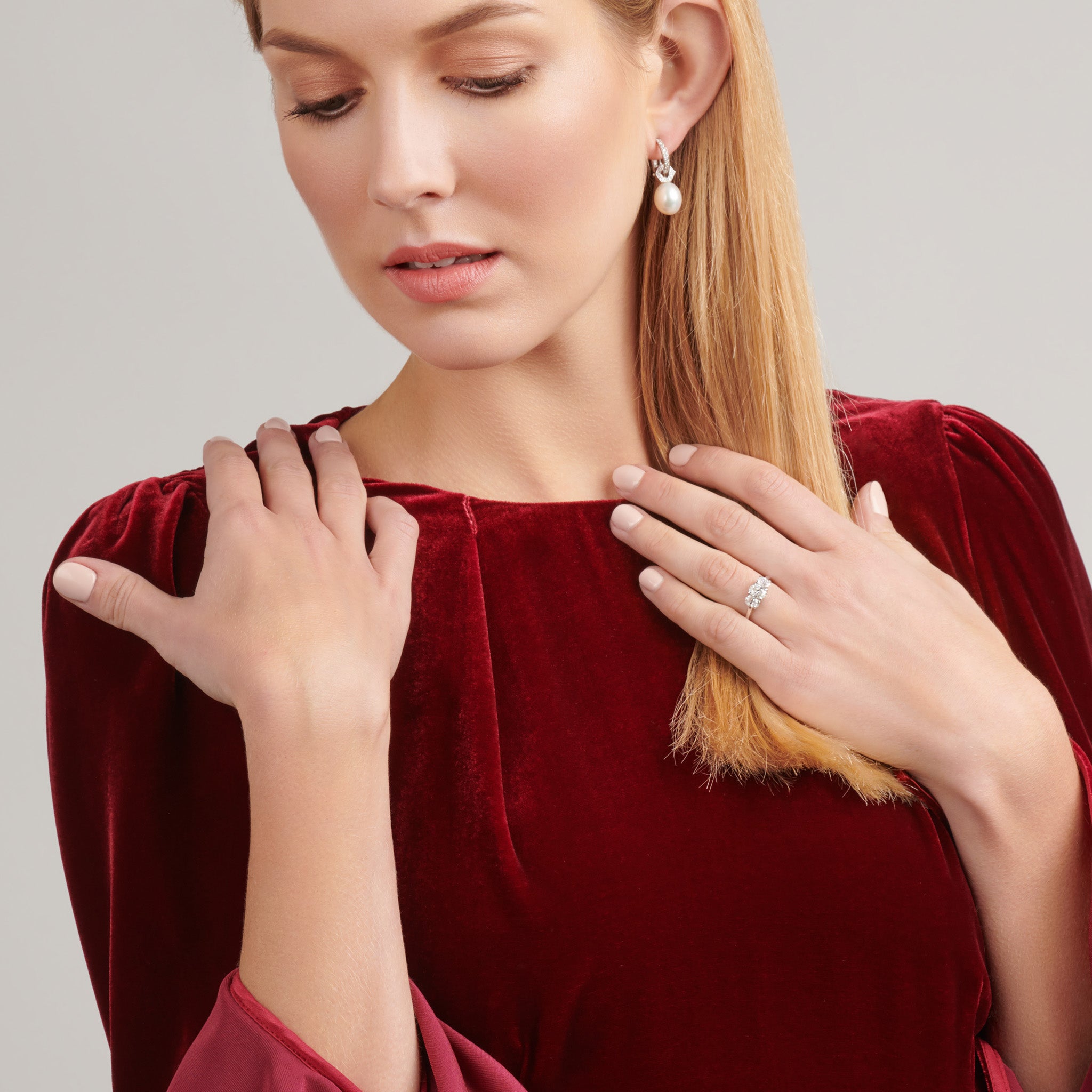 Model wearing a handcrafted 18ct white gold engagement engagement ring with a large central precious stone flanked by two slightly smaller diamonds on each side.