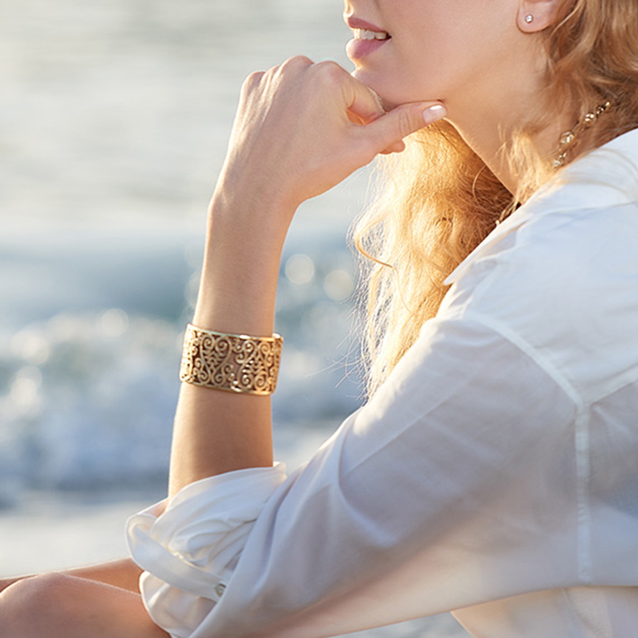 Model wearing a handcrafted yellow gold cuff bracelet featuring stylised fig tree motifs.