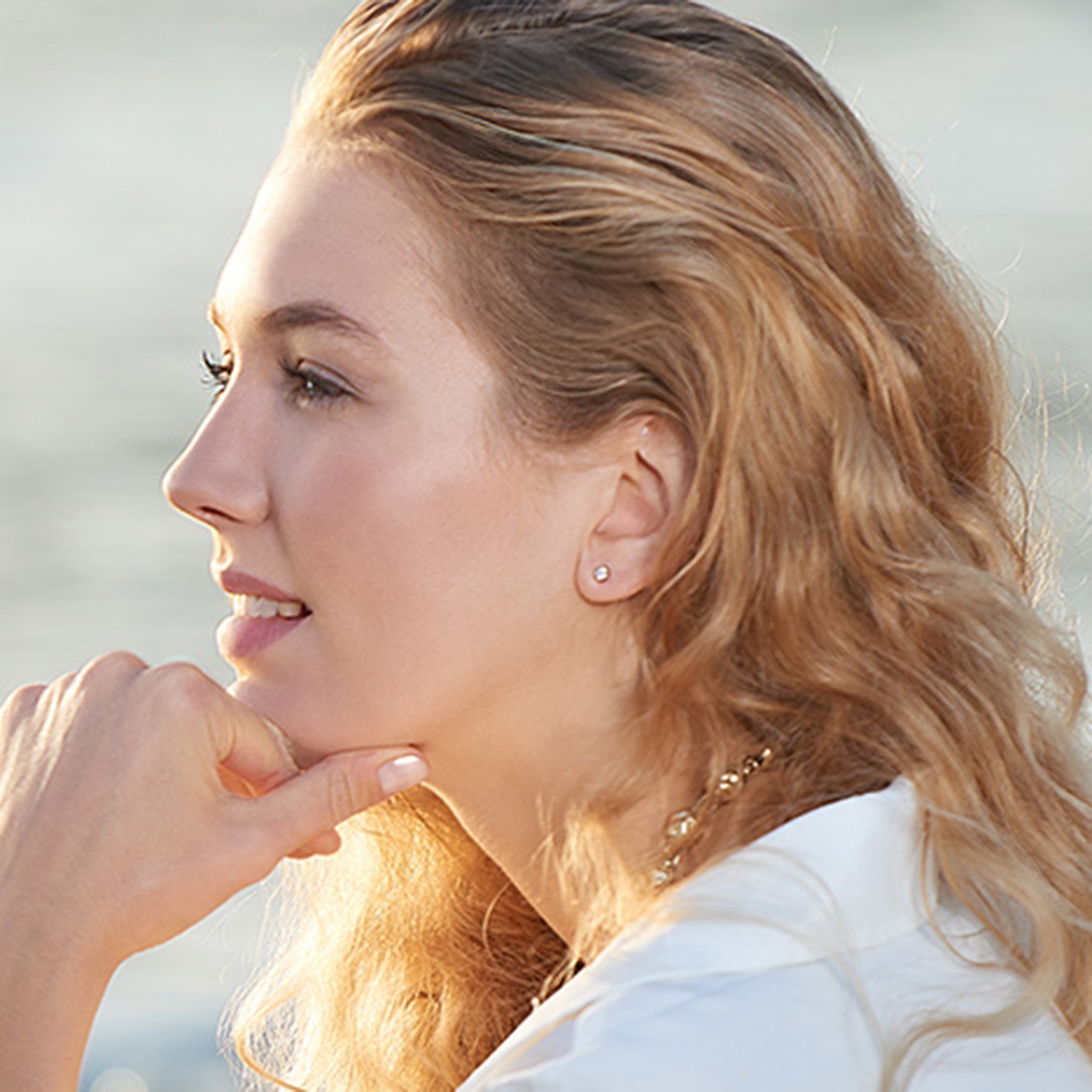 Model wearing handcrafted white gold stud earrings featuring claw set diamonds.